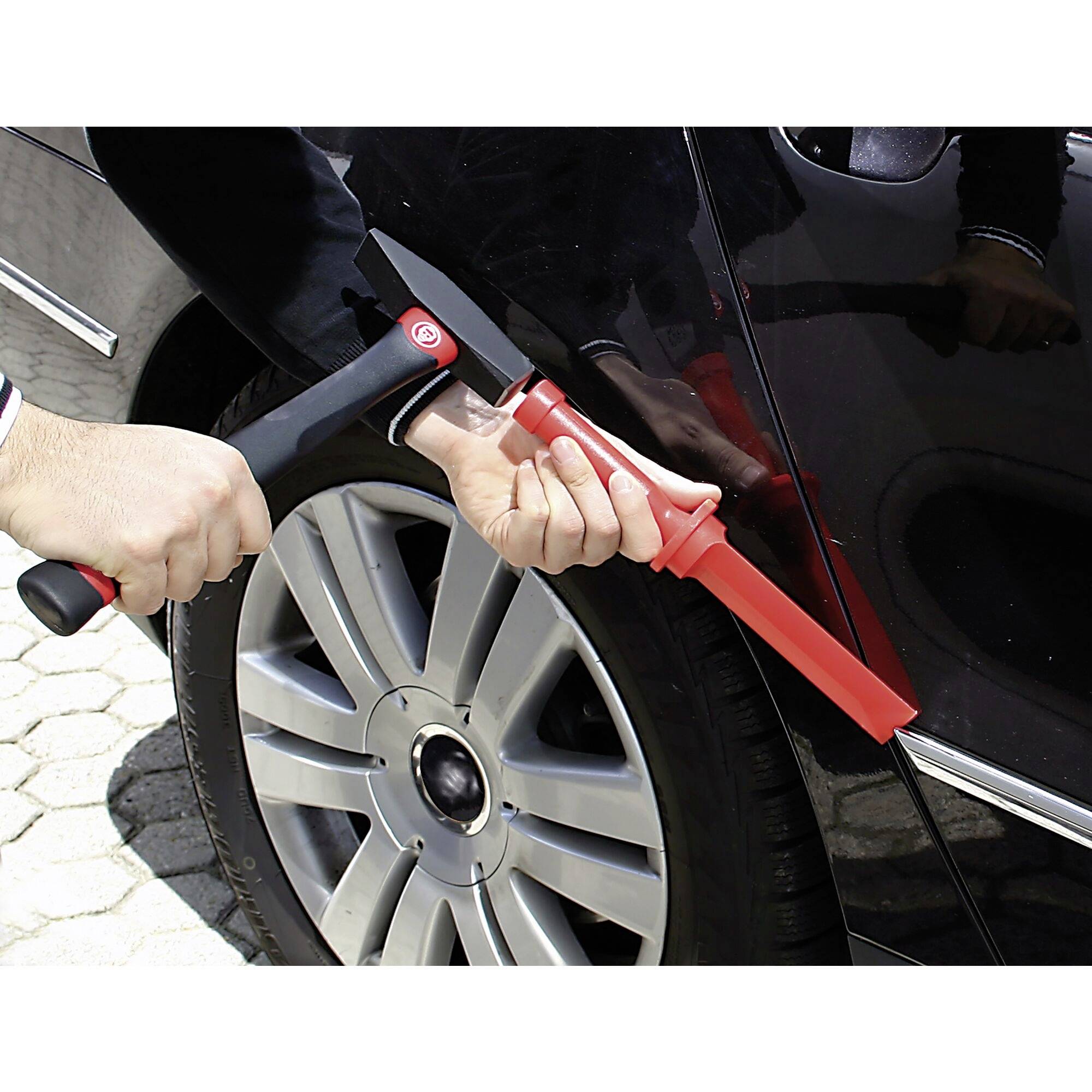 Eine Person verwendet ein rotes Sperrwerkzeug, um das Türschloss eines Autos aufzubrechen.