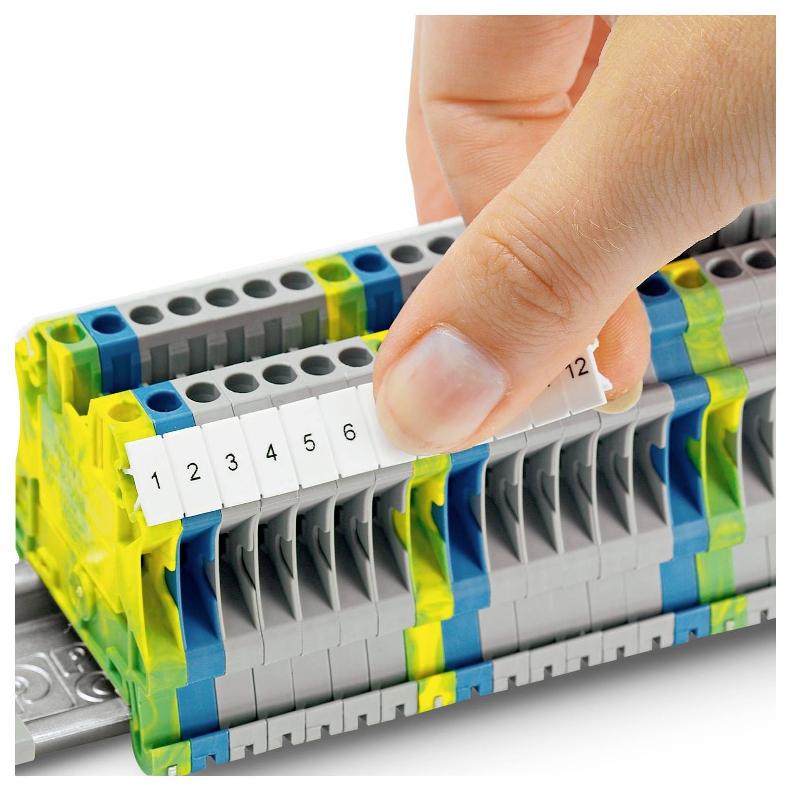 Eine Hand stellt nummerierte Etiketten an einem Elektroklemmenblock ein und zeigt Verbindungspunkte in einer Steuerfeld-Anordnung an.