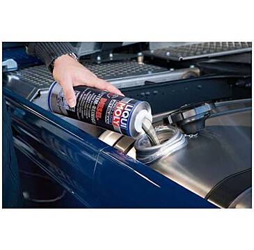 Liqui Moly-Kraftstoffadditiv wird in den Benzintank eines Autos gegossen. Eine Hand hält die Flasche über die offene Tanköffnung eines Fahrzeugs.