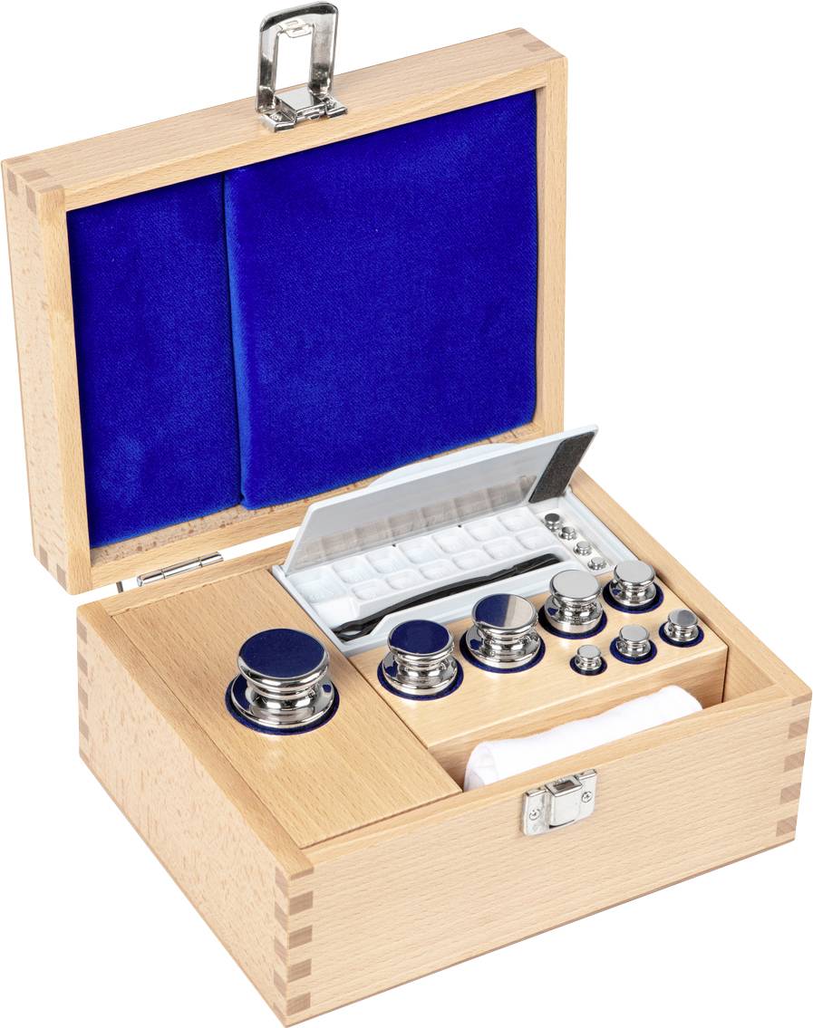 Holzkiste mit geöffnetem Deckel, zeigt ein Gewicht-Set in verschiedenen Größen und eine Pinzette, alles auf blauem Samtfutter.