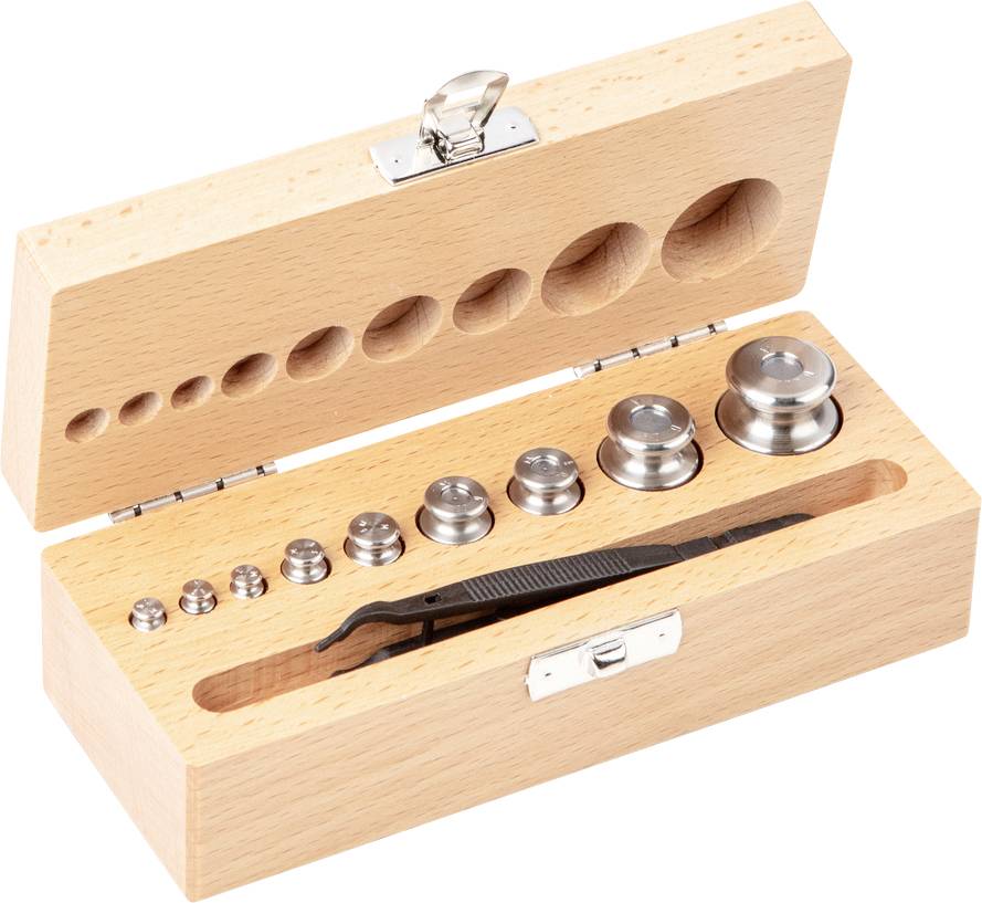 Geöffnete Holzbox mit verschiedenen Metallgewichten und einer Pinzette innen. Verwendet für präzises Wiegen.