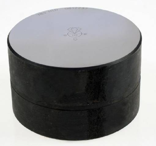 Ein schwarzer metallischer Zylinder mit glatter, silberner Oberseite und gestanztem Symbol auf der Oberfläche.