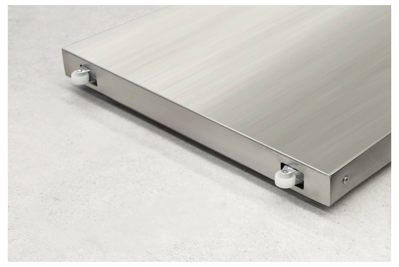 Stahlplatte mit vier kleinen Rädern an den Ecken auf grauem Boden, möglicherweise Teil eines größeren Transport- oder Lagermoduls.