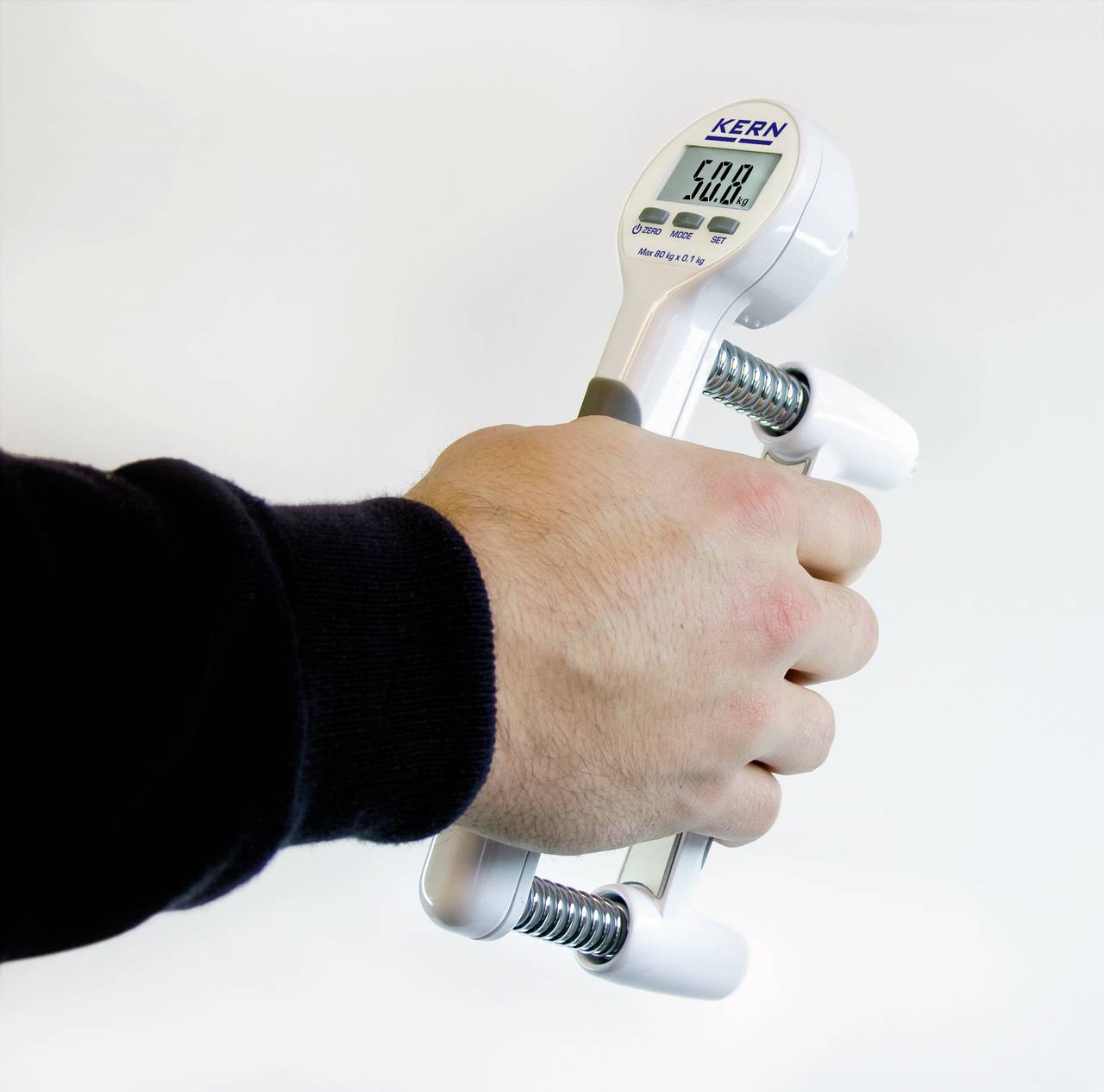 Eine Person hält ein digitales Handdynamometer in der Hand, das 50,8 kg anzeigt. Gerät misst die Griffkraft.