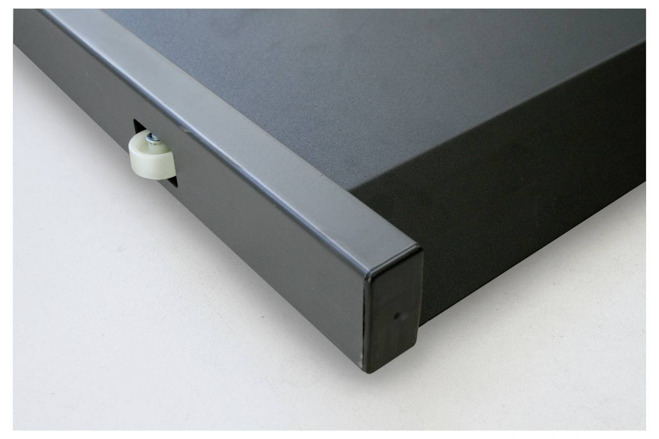 Nahaufnahme einer schwarzen Metallkiste oder Schublade, teilweise geöffnet, mit einem kleinen weißen Rad an der Seite.