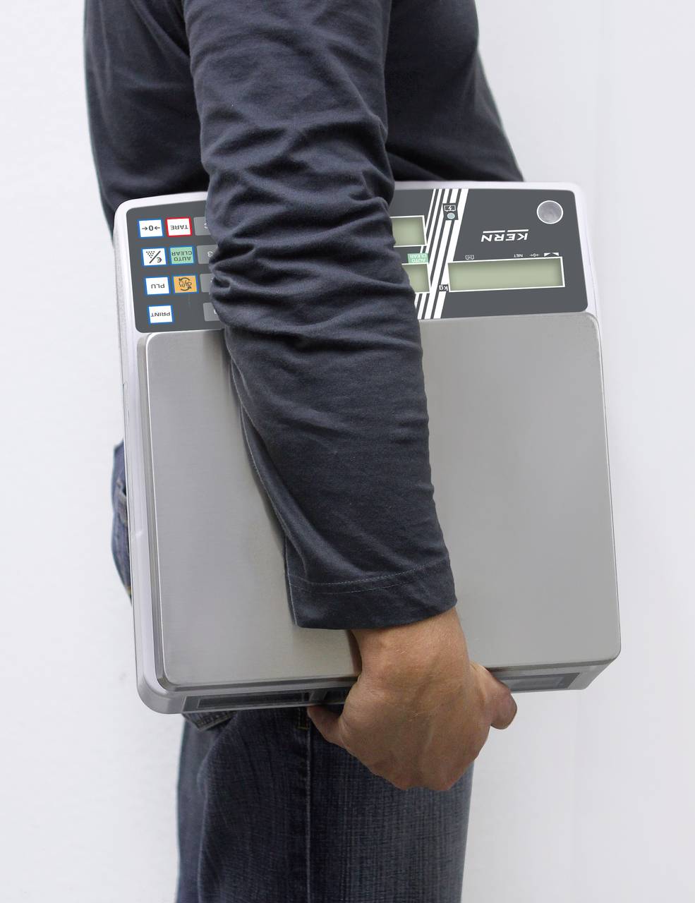 Eine Person trägt ein elektronisches Gerät, das wie ein Wahlgerät aussieht. Es hat Tasten mit Symbolen und zwei digitale Anzeigen.