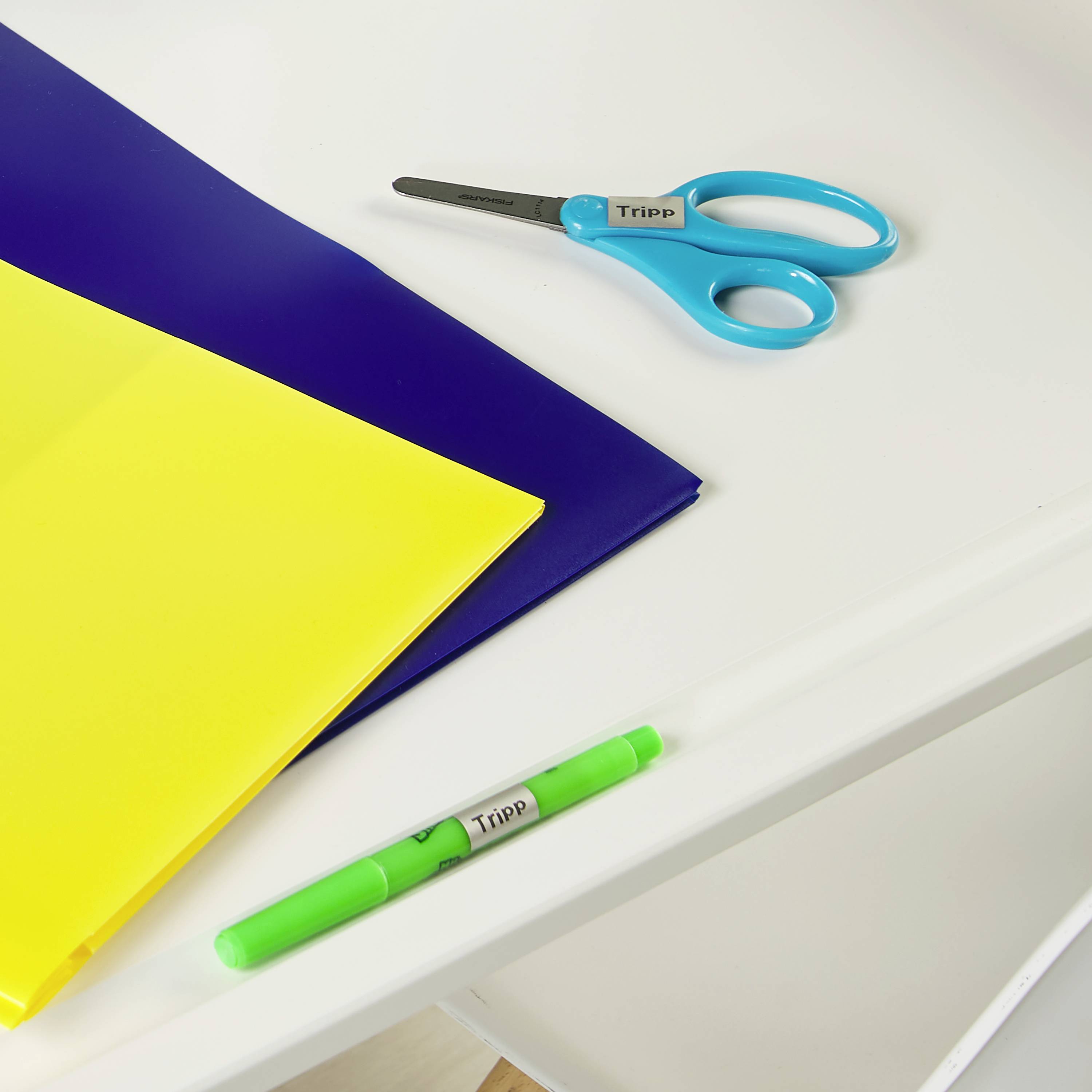 Bürotisch mit blauer und gelber Mappe, einer Schere und einem grünen Stift.