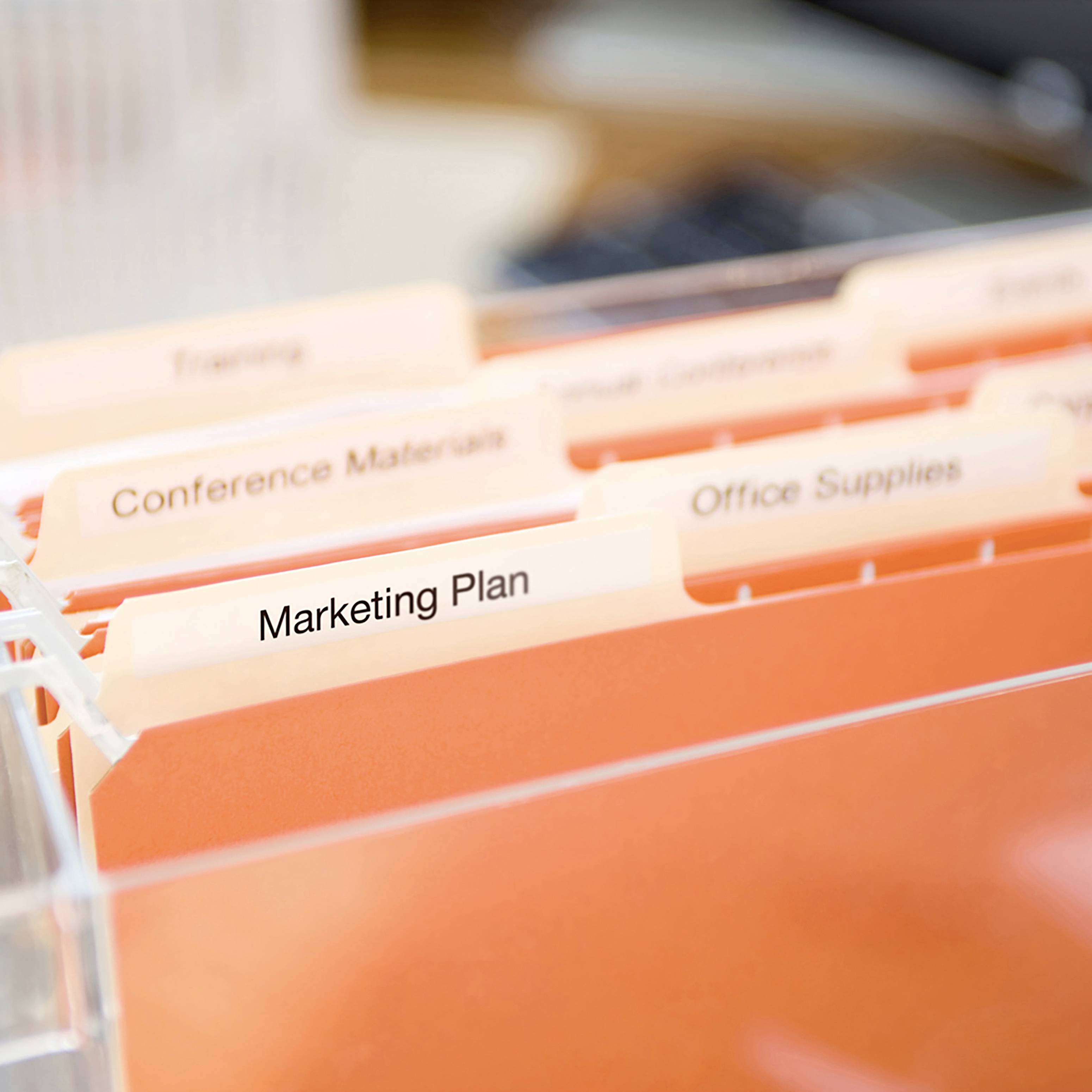 Eine orangefarbene Dateiablage mit der Beschriftung 'Marketing Plan' und weiteren Kategorien im Hintergrund.
