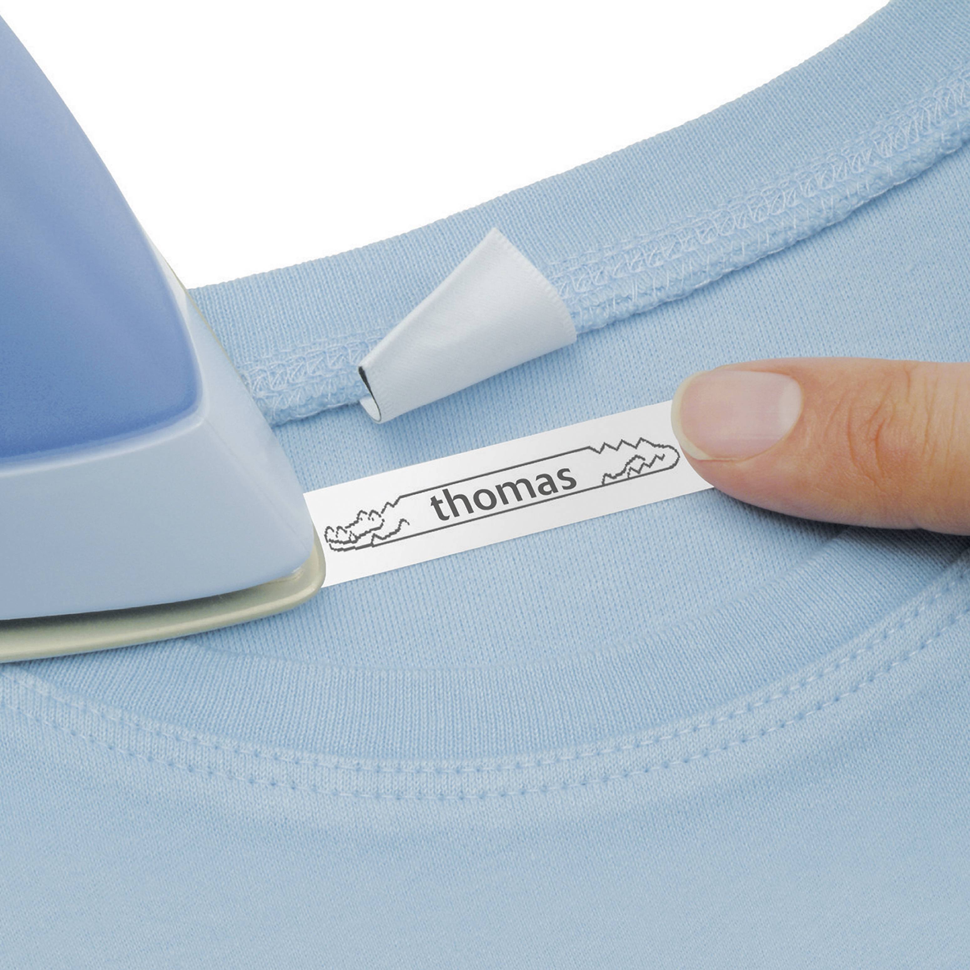 Eine blaue Bügeleisenspitze drückt ein Namensetikett mit der Aufschrift 'thomas' auf ein hellblaues T-Shirt.