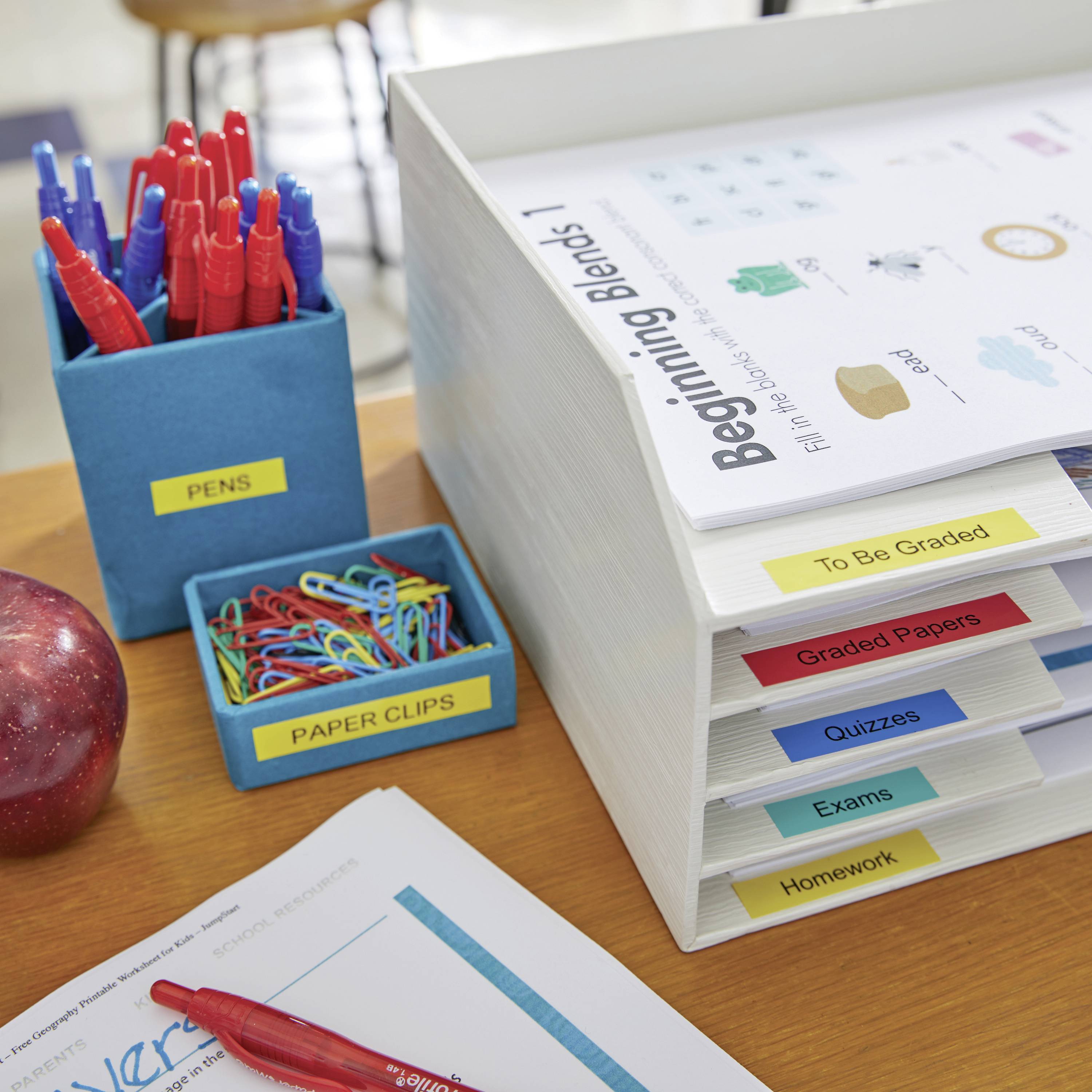 Organisierter Schreibtisch mit beschriftetem Papierablagesystem: 'To Be Graded', 'Graded Papers', 'Paper Clips', 'Exams', 'Homework'.
