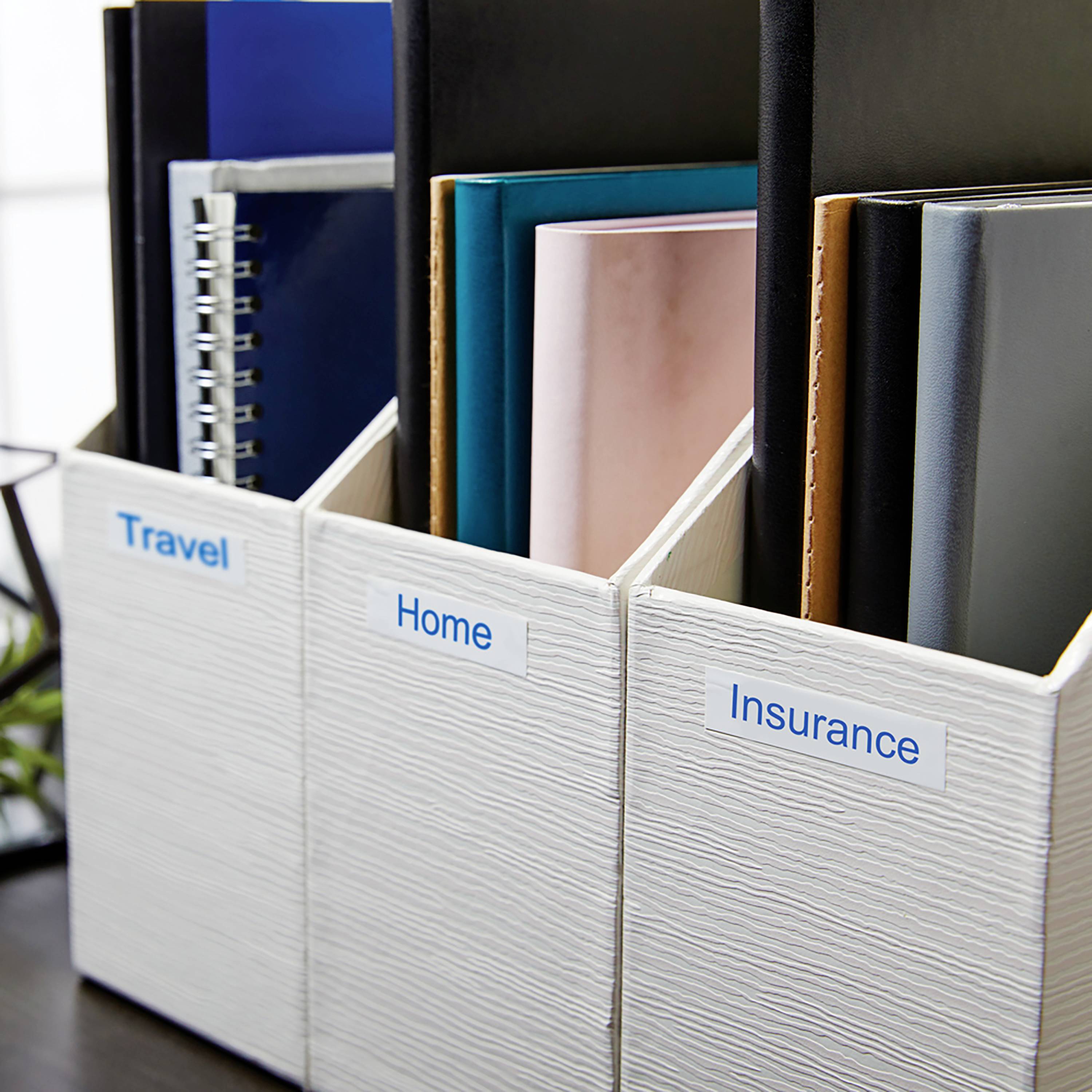 Ordner mit Etiketten: 'Travel', 'Home', 'Insurance'. Enthält verschiedene gebundene Unterlagen, die organisiert und zugänglich sind.