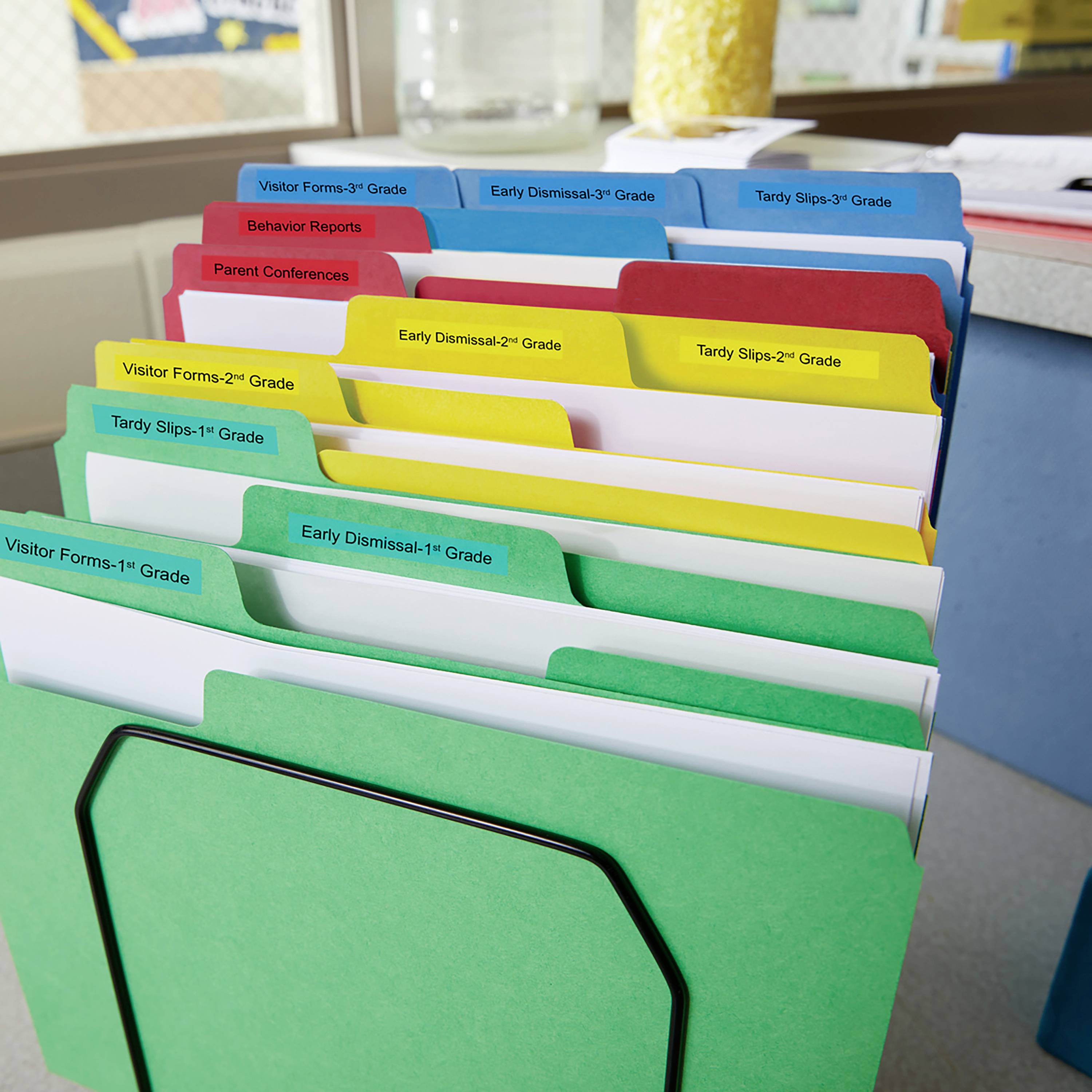 Ablage mit farbigen Trennblättern für verschiedene Schulthemen, wie Verhaltensberichte und Entlassungsscheine, auf einem Schreibtisch.