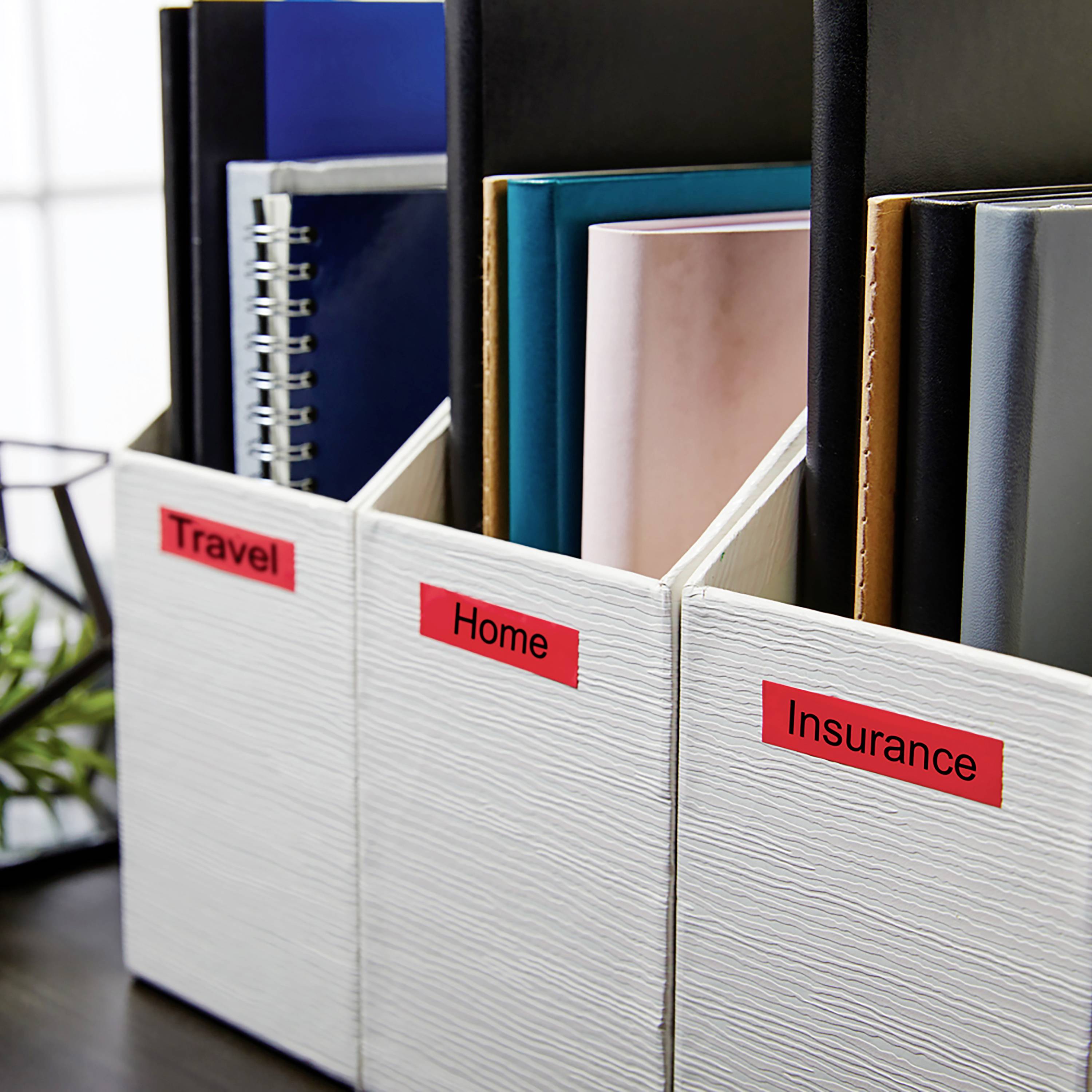 Aktenschuber mit Beschriftungen 'Travel', 'Home', 'Insurance', gefüllt mit Ordnern und Notizbüchern, auf einem Bürotisch.