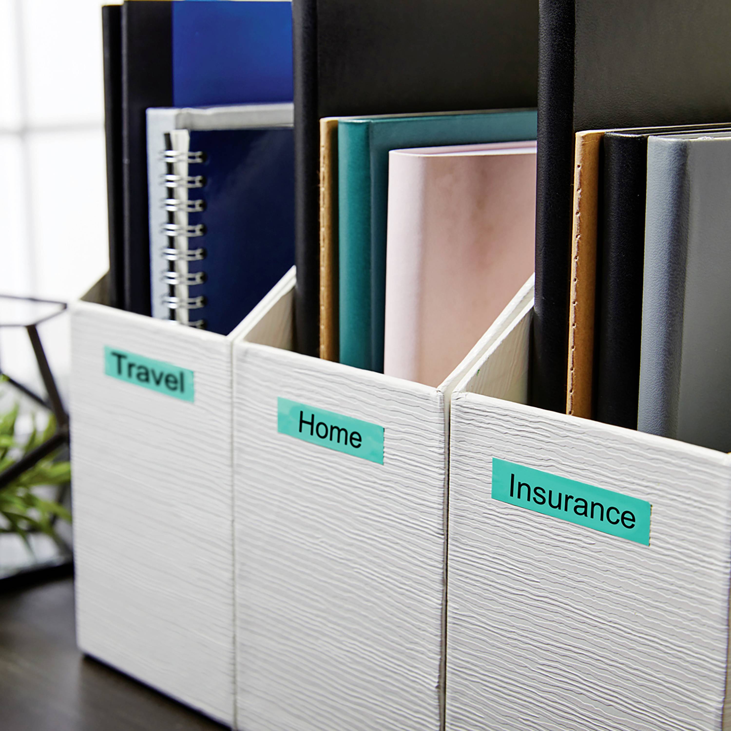 Drei weiße Ablageboxen beschriftet mit 'Travel', 'Home' und 'Insurance', gefüllt mit Ordnern und Notizbüchern, stehen nebeneinander.