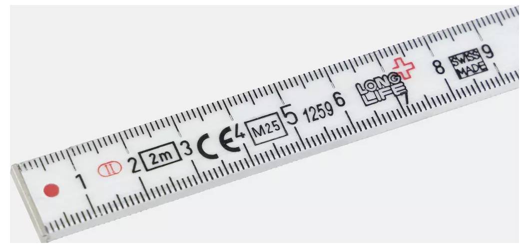 Ein Nahaufnahmefoto eines weißen Messstabs mit schwarzen und roten Markierungen, Zahlen und Zertifizierungssymbolen.