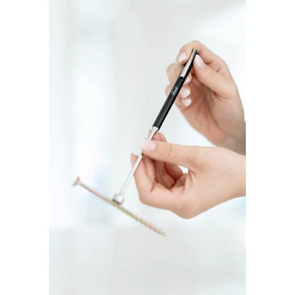 Eine Person hält einen schwarz-silbernen Stift und ein goldfarbenes Smartphone in den Händen vor einem unscharfen Hintergrund.