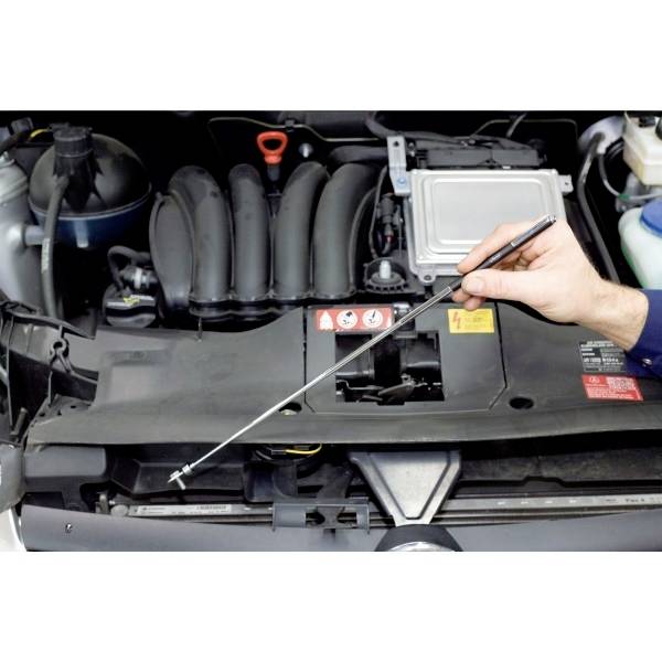 Eine Hand zieht den Ölmessstab aus einem Auto, um den Ölstand zu überprüfen.