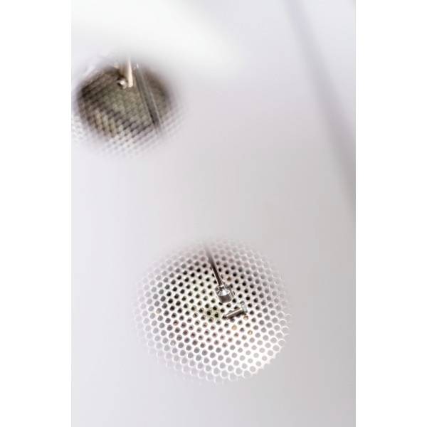 Eine metallene Struktur mit einem runden Raster, das Licht in einem Raum reflektiert.