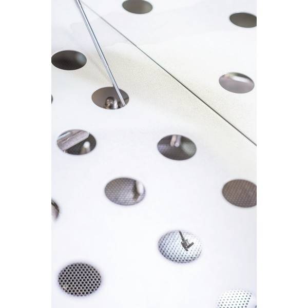 Eine Nahaufnahme von Lochblech mit kreisförmigen Öffnungen. Licht fällt durch die Löcher und erzeugt ein interessantes Muster.