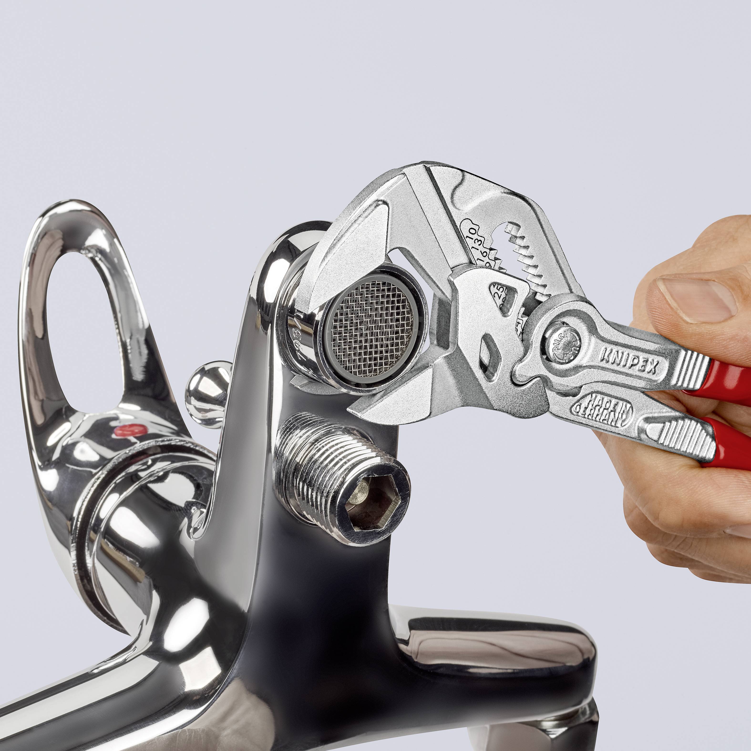 Eine Hand benutzt eine Zange, um einen Wasserhahn zu reparieren, auf grauem Hintergrund.
