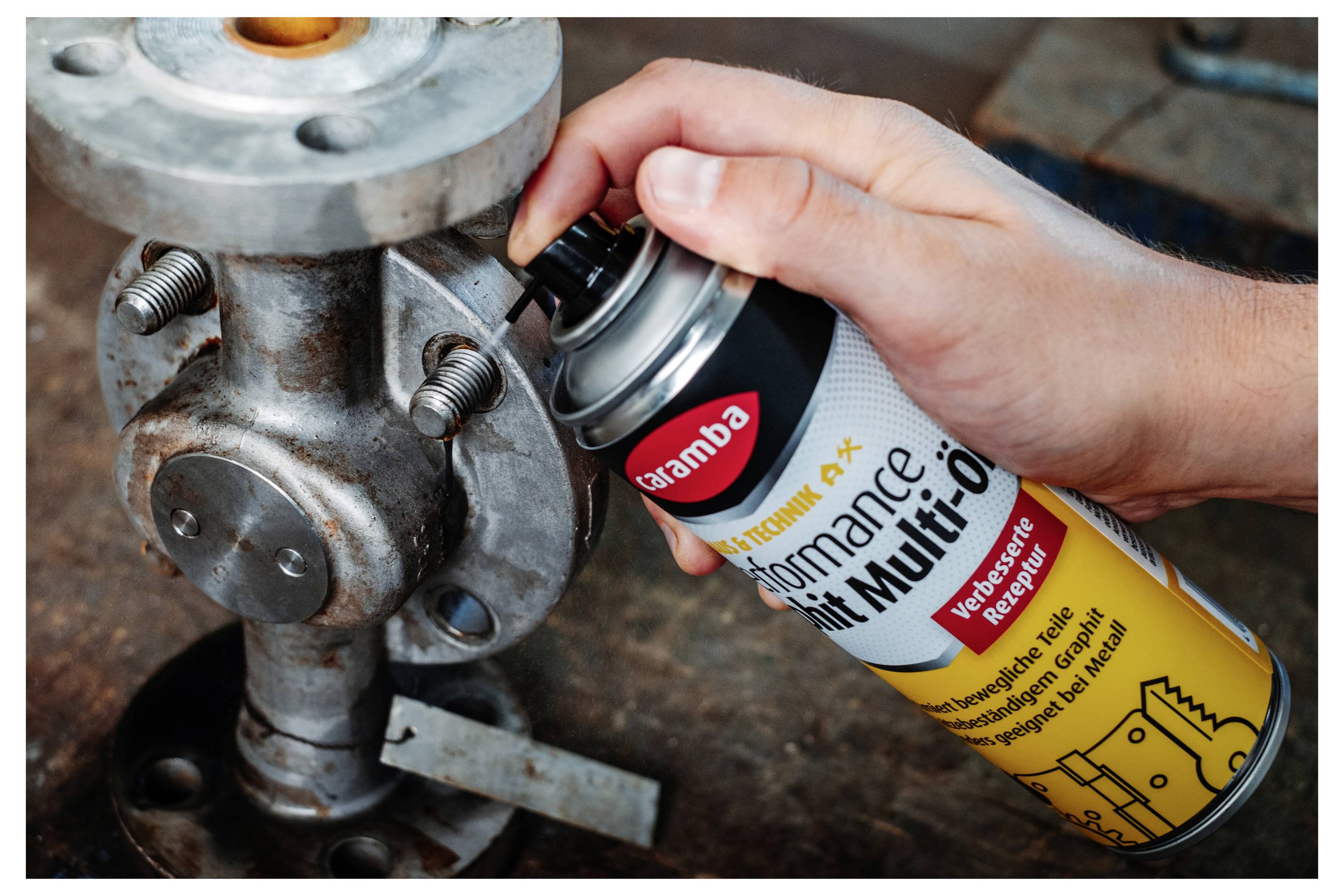 Handsprays 'aramba' Performance Multi-Öl-Schmierstoff auf eine rostige Metallventilbaugruppe in einer industriellen Umgebung auf.