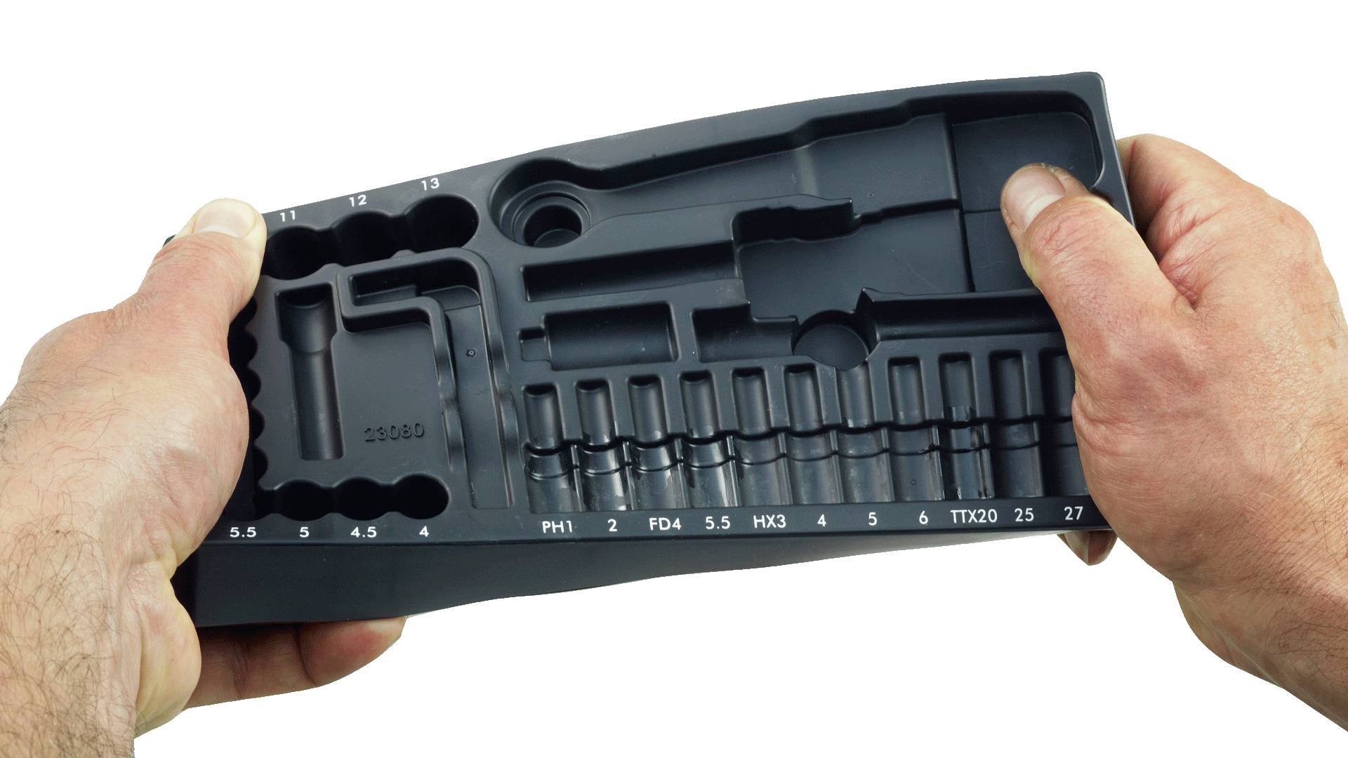 Zwei Hände halten einen leeren schwarzen Plastikwerkzeugkoffer mit mehreren Fächern für verschiedene Werkzeugbits, die mit Zahlen und Größen beschriftet sind.