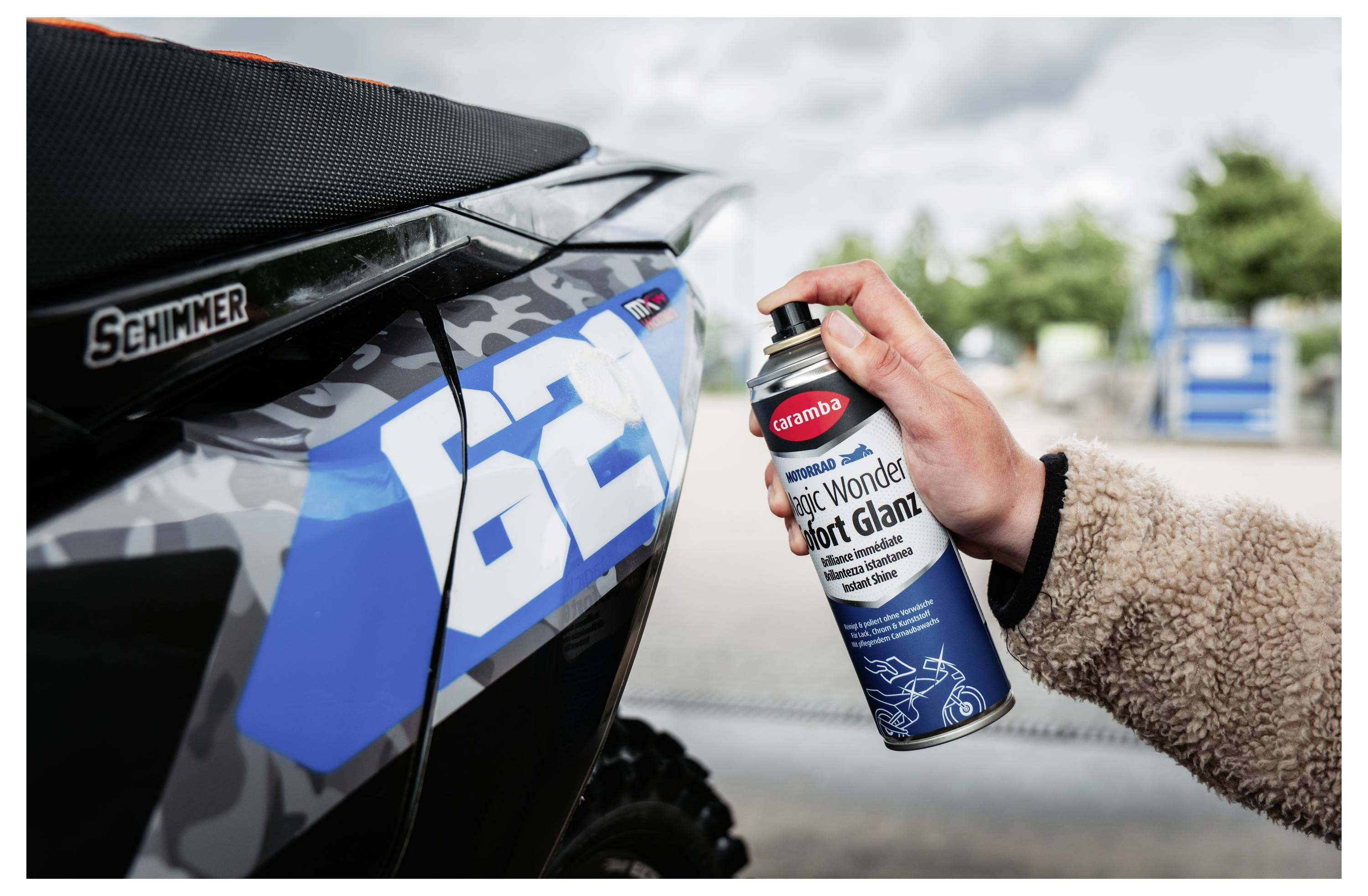 Handsprays 'Muc-Off' 'Silk Matt Finish' auf einem blauen Schmutzrad-Panel mit der Nummer 62 neben einem 'Schimmer'-Sattel.