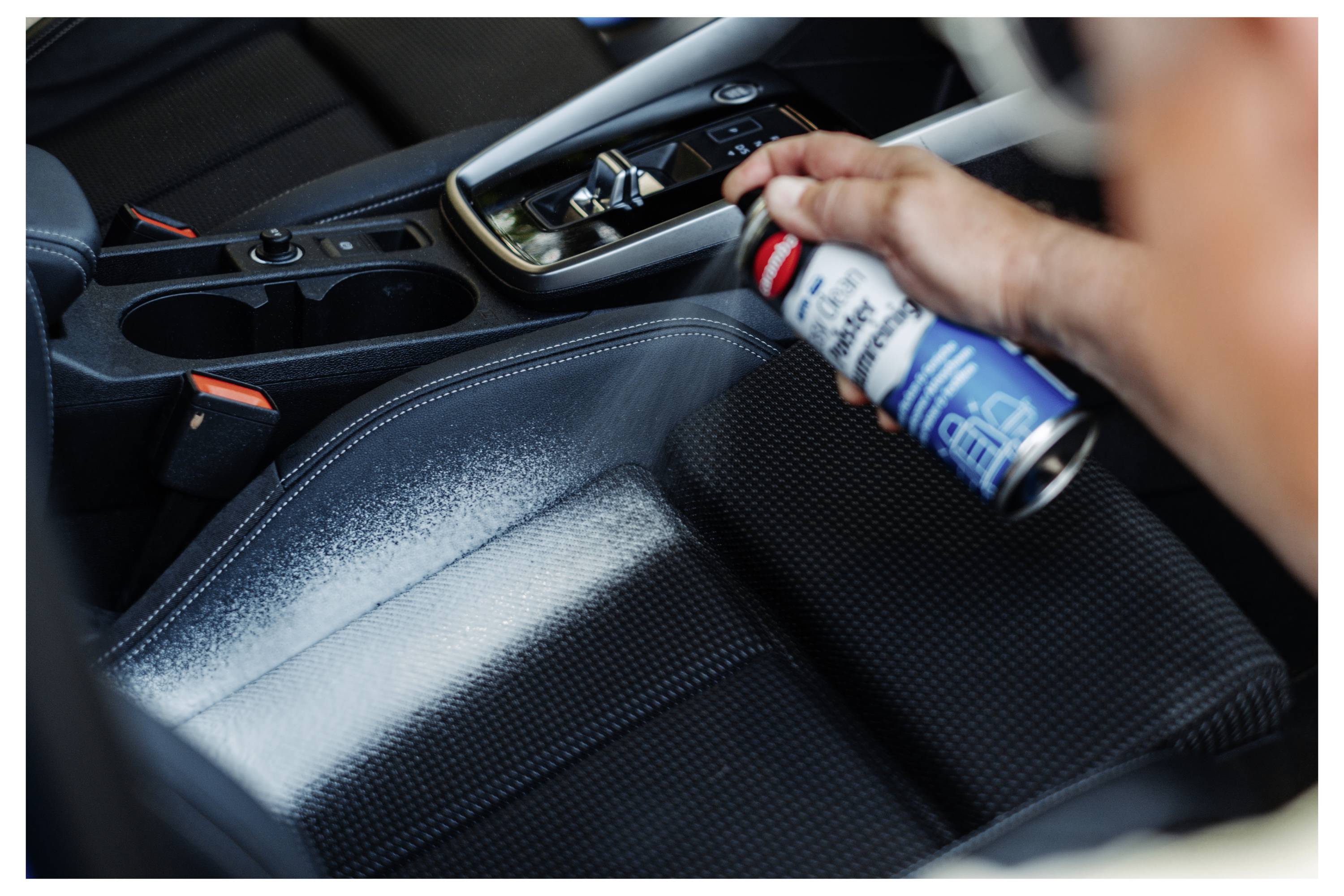 Handreinigung und detaillierte Reinigung der Mittelkonsole eines Autos mit Sprühreiniger.