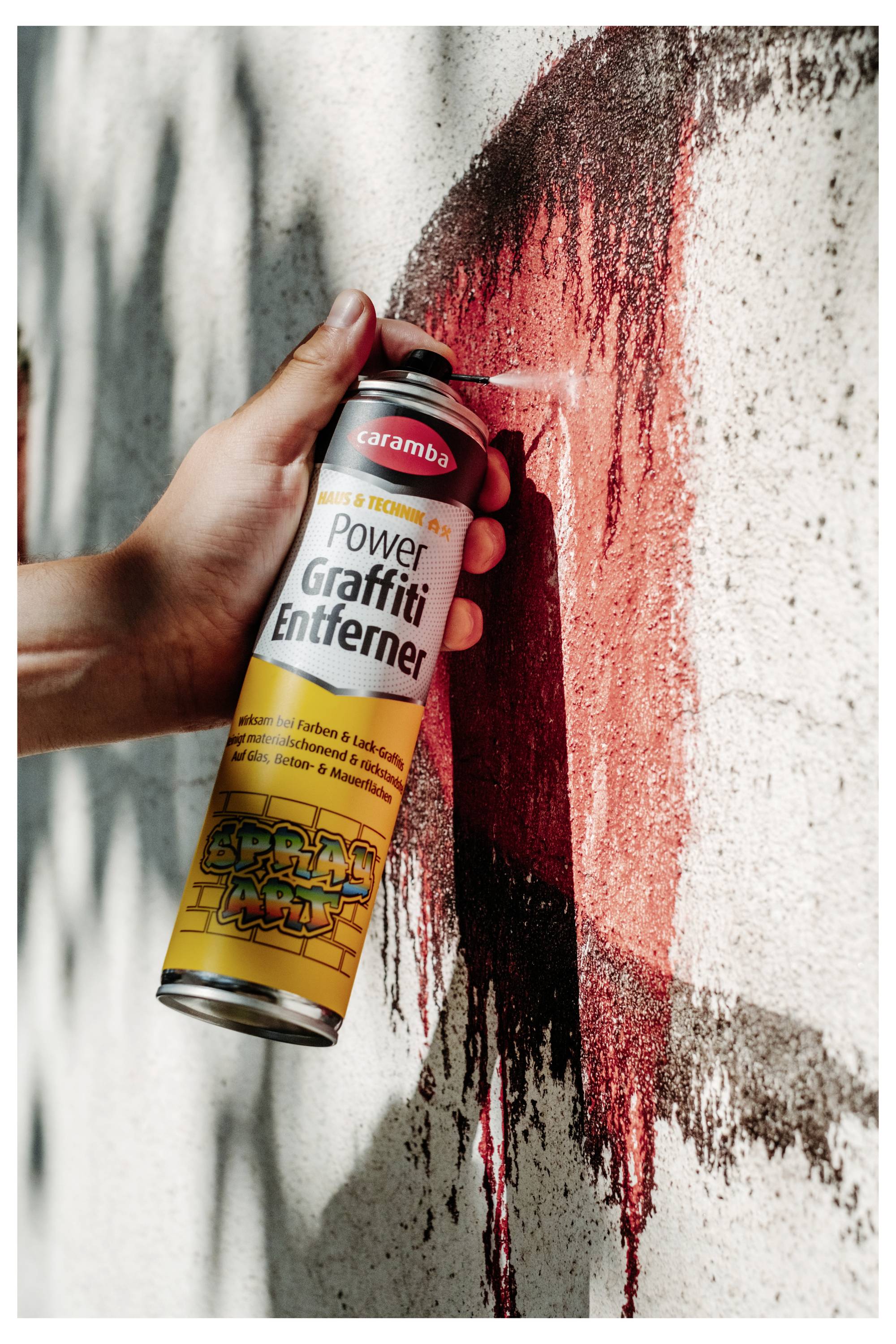 Eine Hand sprüht rote Farbe aus einer 