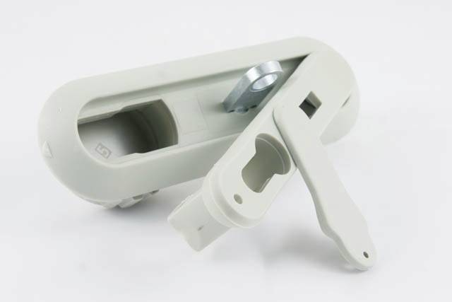 Grauer, ovaler Fenstergriff mit zwei beweglichen Hebeln. Der Griff hat Öffnungen und ist für Fenster- oder Türmechanismen gedacht.