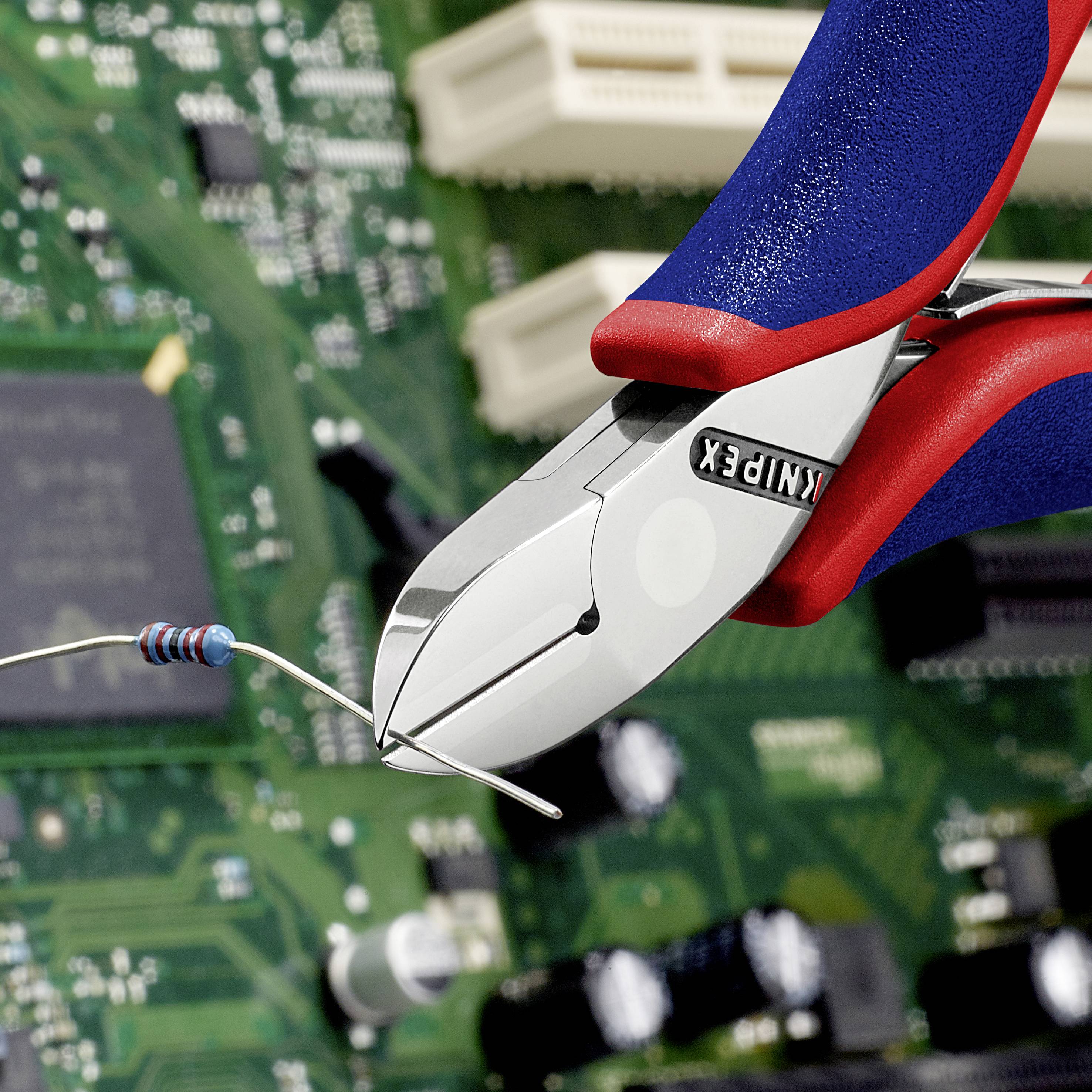 Eine nahaufnahme eines elektronischen Drahtes, der mit einem roten und blauen Seitenschneider durchtrennt wird, vor einer Leiterplatte.