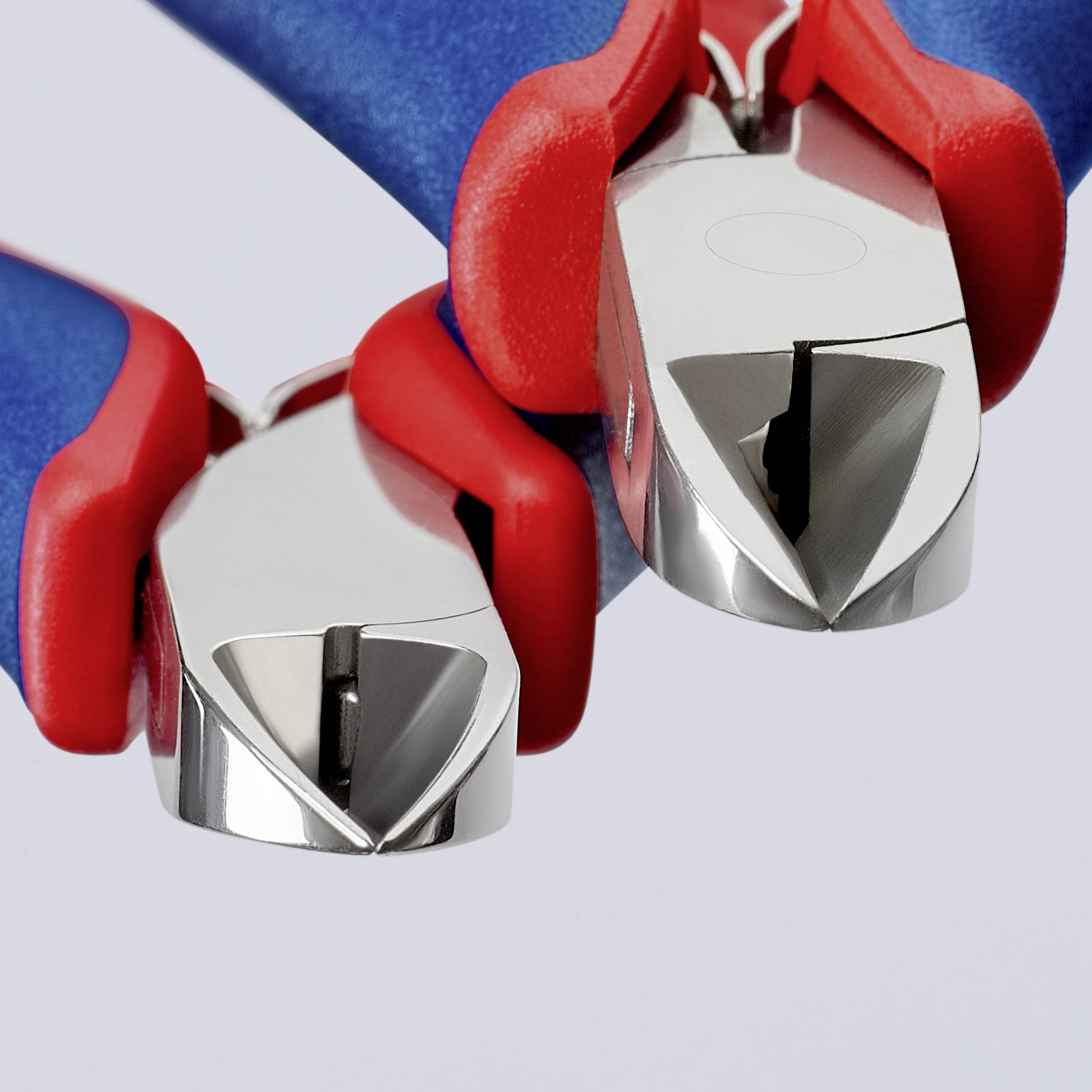 Zwei rote und blaue Zangen mit glänzenden Metallschneidklingen, nahe beieinander liegend, auf grauem Hintergrund.