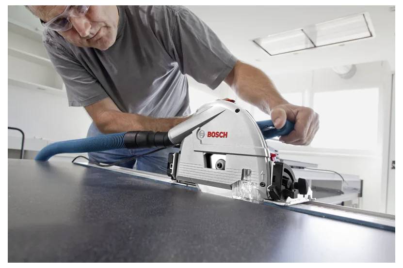 Eine Person, die ein Bosch-Elektrowerkzeug verwendet, um ein Materialblatt mit präziser Konzentration zu schneiden.