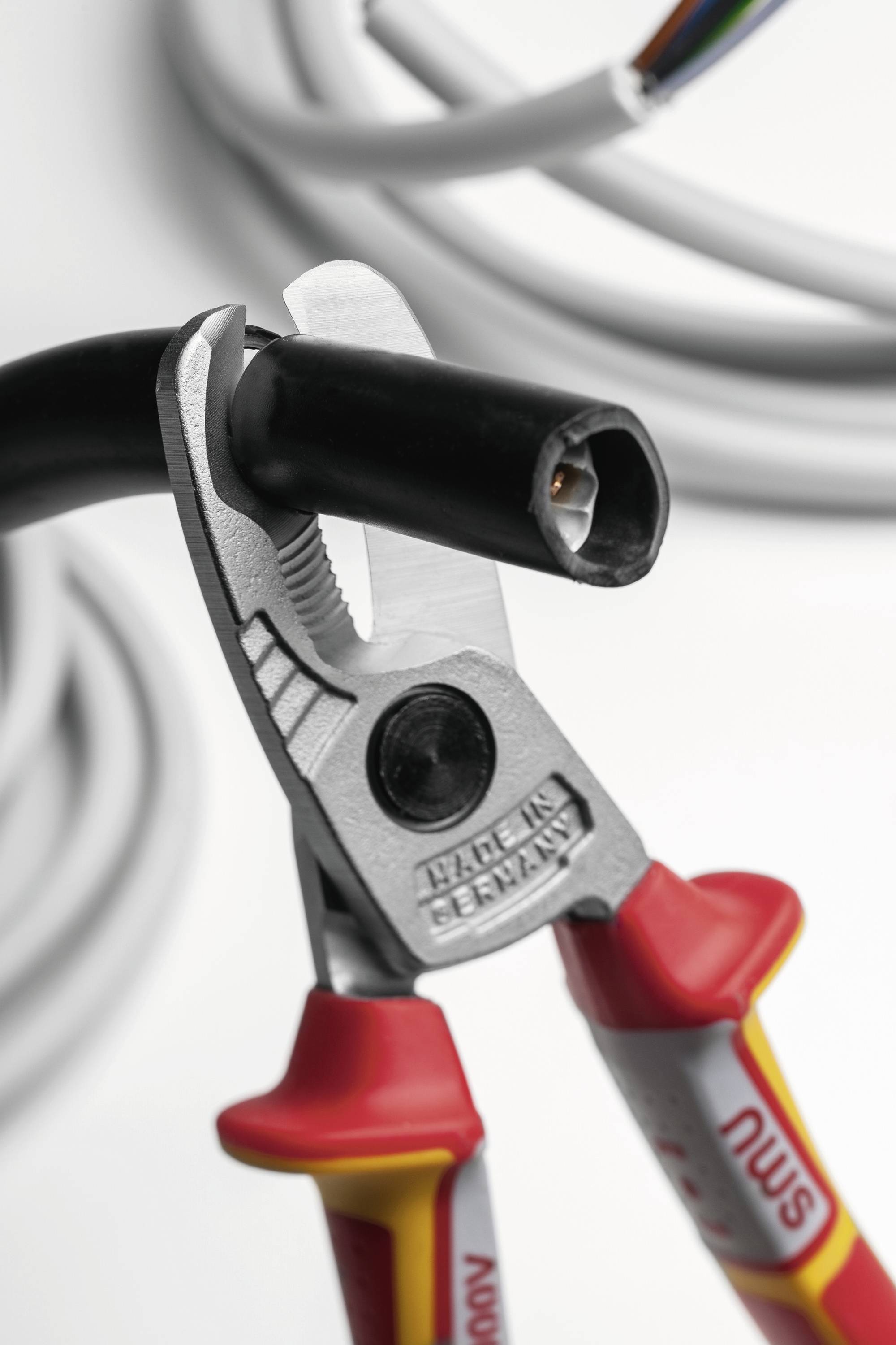 „Nahaufnahme eines isolierten Kabels, das mit Kabeldrahtschneidern durchtrennt wird, mit Betonung auf Sicherheit und Präzision bei elektrischen Arbeiten.