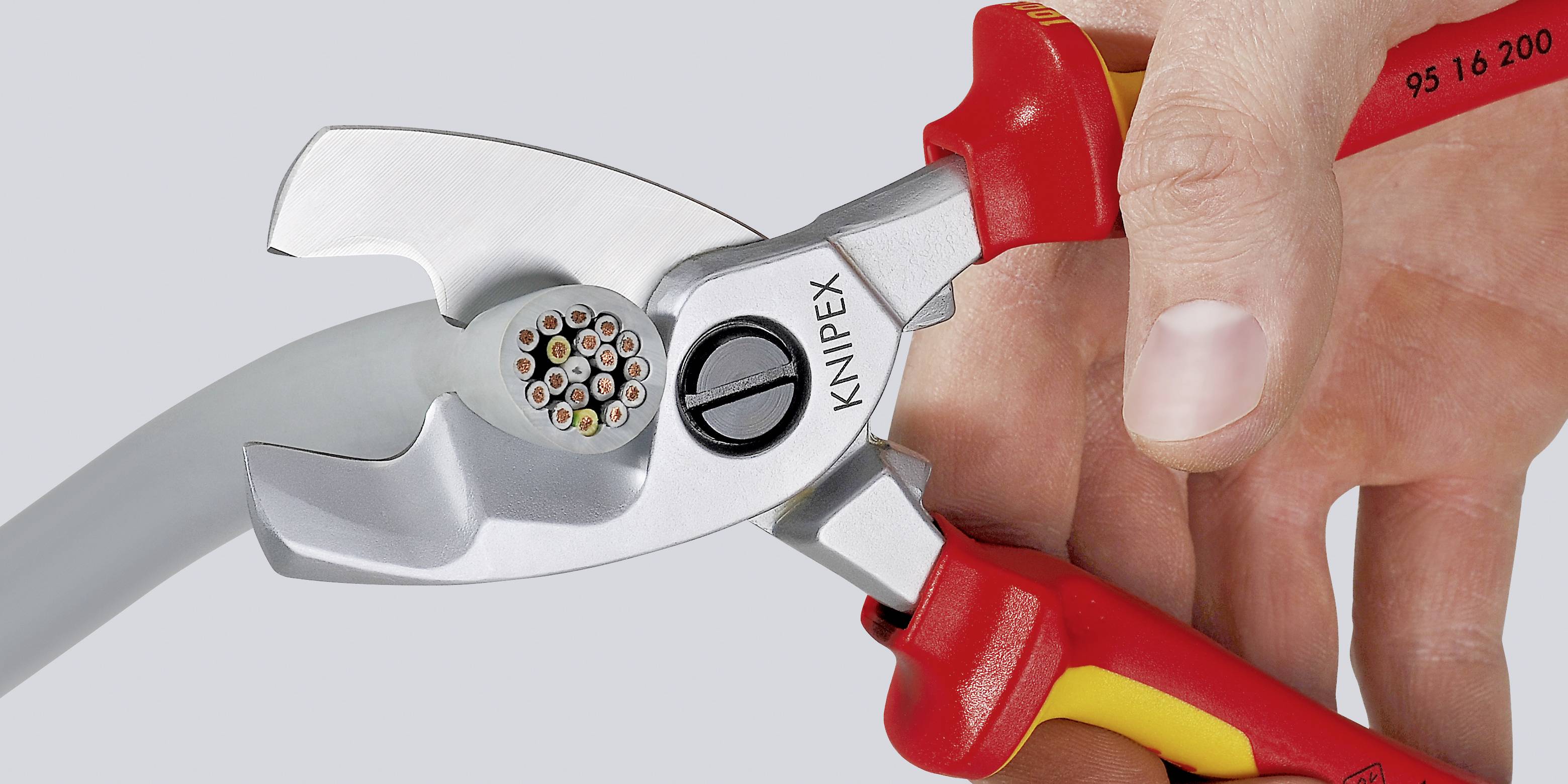 Eine Hand hält eine rote Kabelschere der Marke Knipex, während sie ein mehradriges Kabel schneidet.