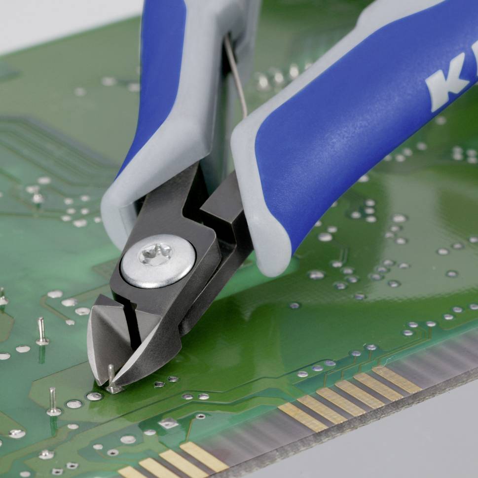 Eine Zange schneidet Drähte auf einer Leiterplatte ab, zeigt Elektronikreparatur oder -montage.