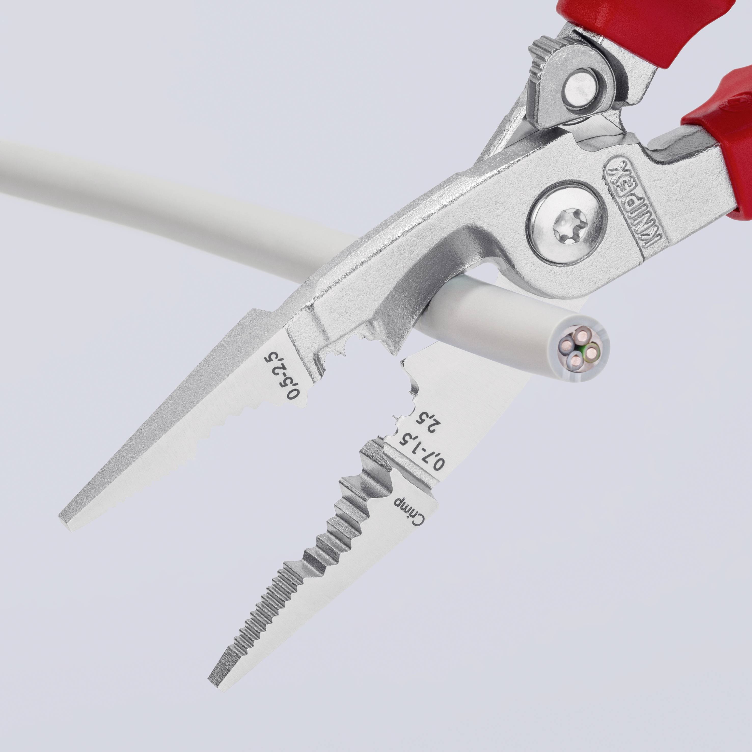 Eine Zange schneidet ein weißes Kabel mit mehreren Drähten im Querschnitt. Die Zange hat unterschiedliche Schneidbereiche.