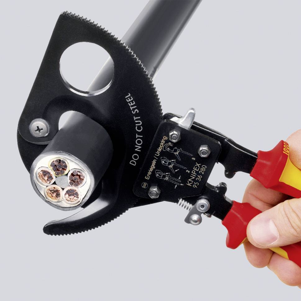 Eine Hand hält ein Kabelschneiderwerkzeug, das ein dickes, mehradriges Kabel umschließt. Aufschrift auf dem Werkzeug: 'DO NOT CUT STEEL'.