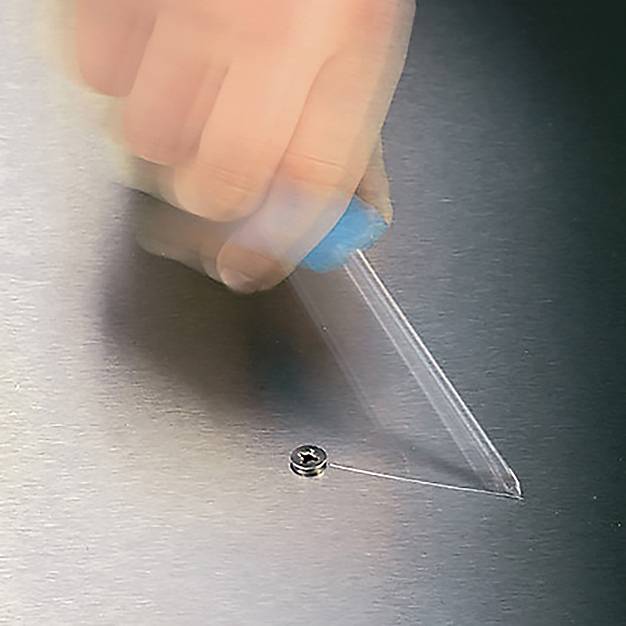 Eine Hand hält ein Plastikwerkzeug und zieht einen Schutzfilm von einer Blechoberfläche. Eine Schraube ist am Rand des Metalls sichtbar.