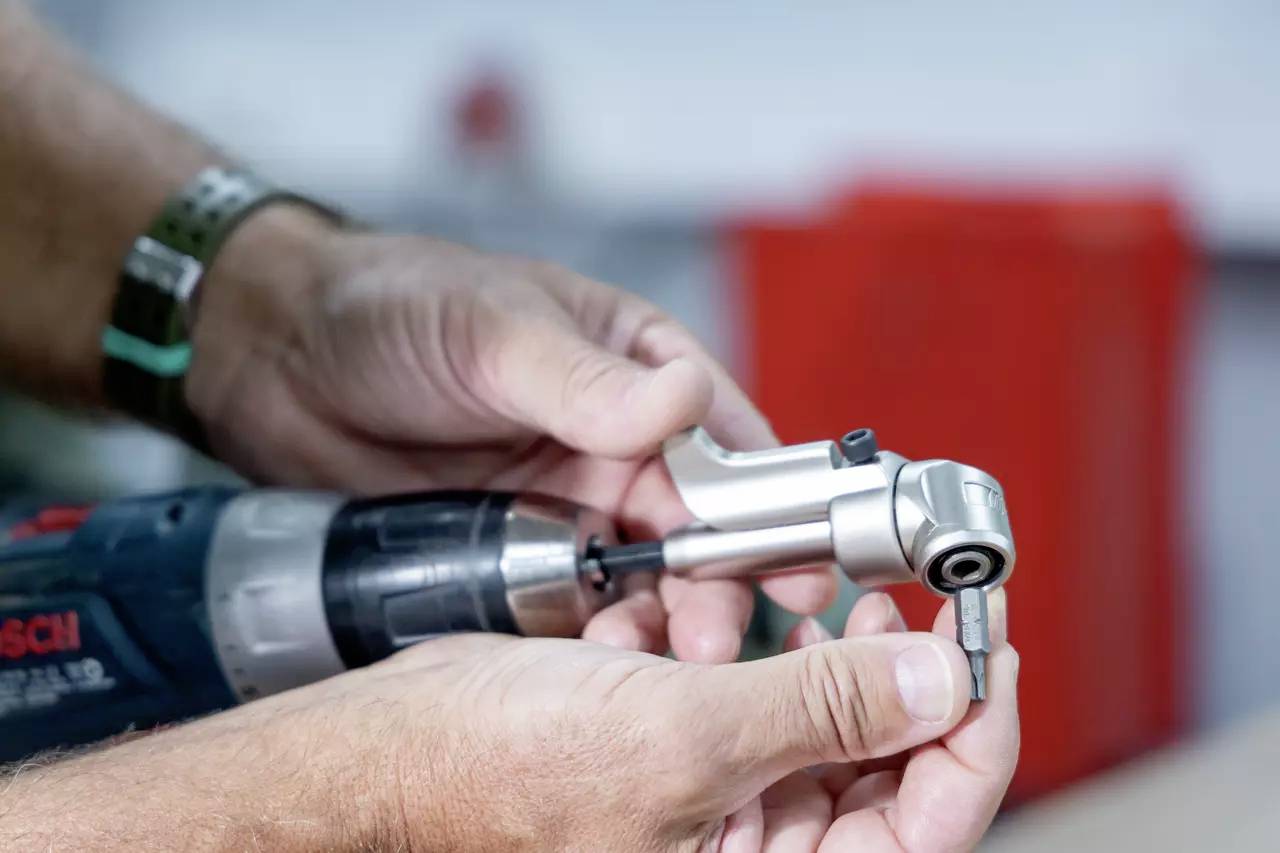 Eine Person befestigt einen Metallbohrer an einer Bohrmaschine und demonstriert damit den Vorgang der Vorbereitung eines Bohrers für die Verwendung in einer Werkstattumgebung.