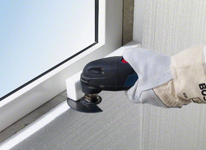 Handwerker verwendet ein oszillierendes Werkzeug, um präzise an einem Fensterrahmen zu arbeiten. Detailarbeit an einer Kante.