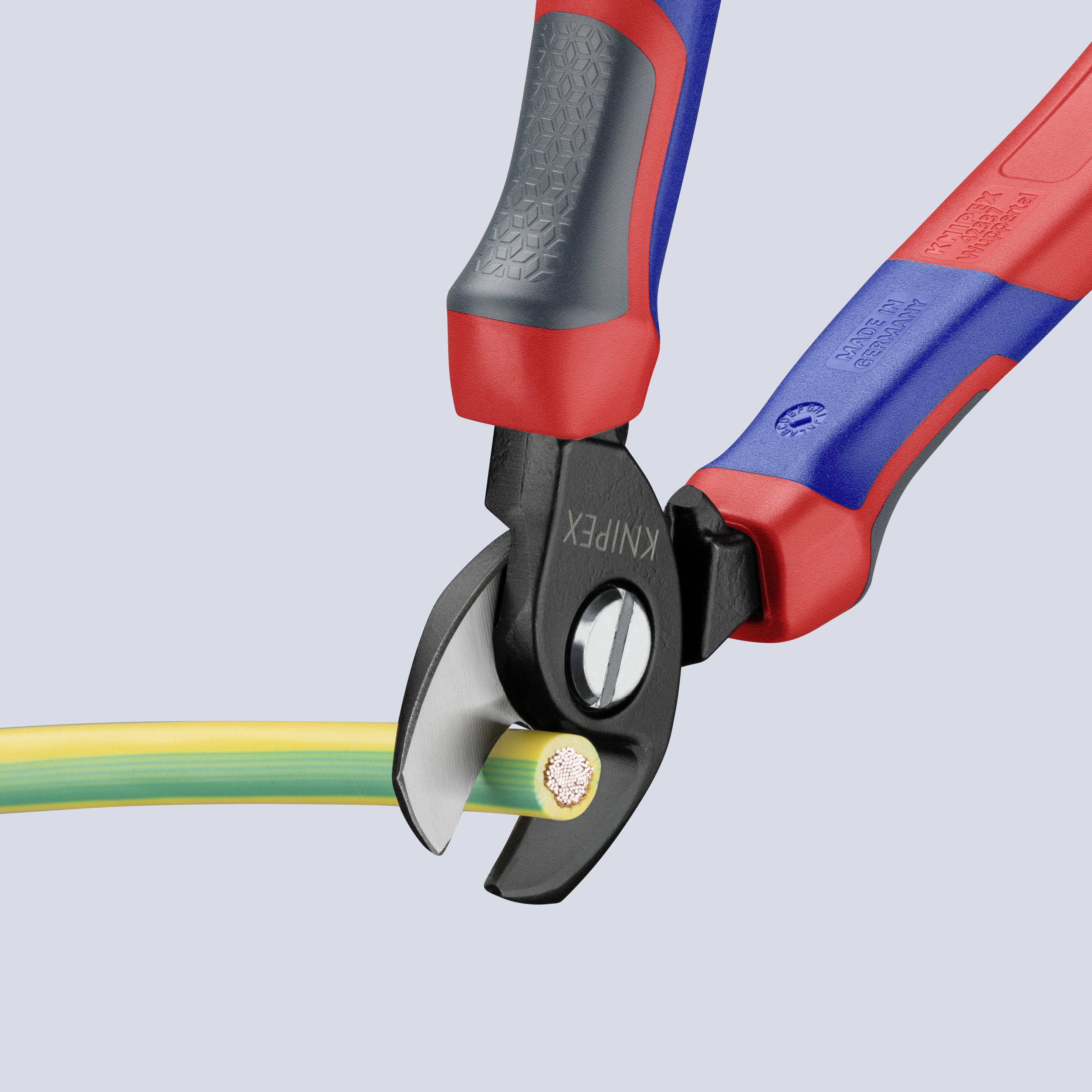 Eine Zange schneidet ein dickes, rundes Kabel. Die Zangengriffe sind rot und blau.