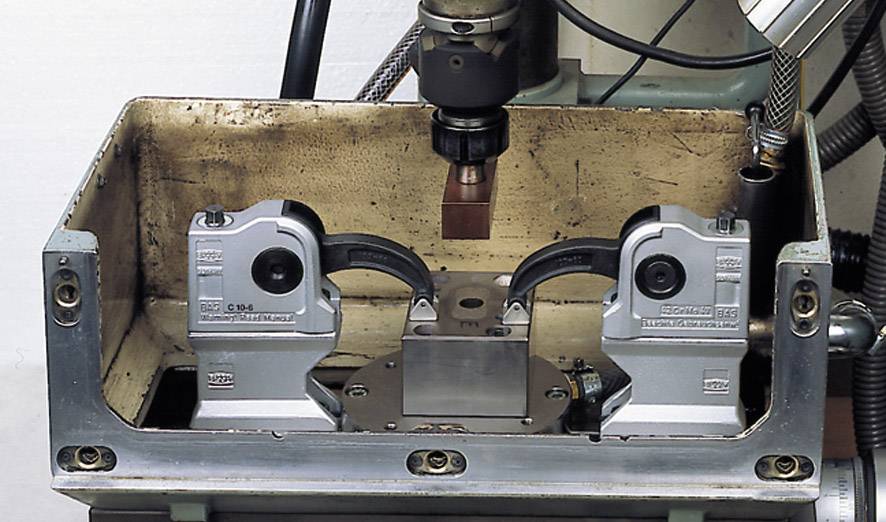 Eine Metallmaschine mit Werkzeug zur Bearbeitung eines Werkstücks ist zu sehen, umgeben von verschiedenen mechanischen Komponenten.