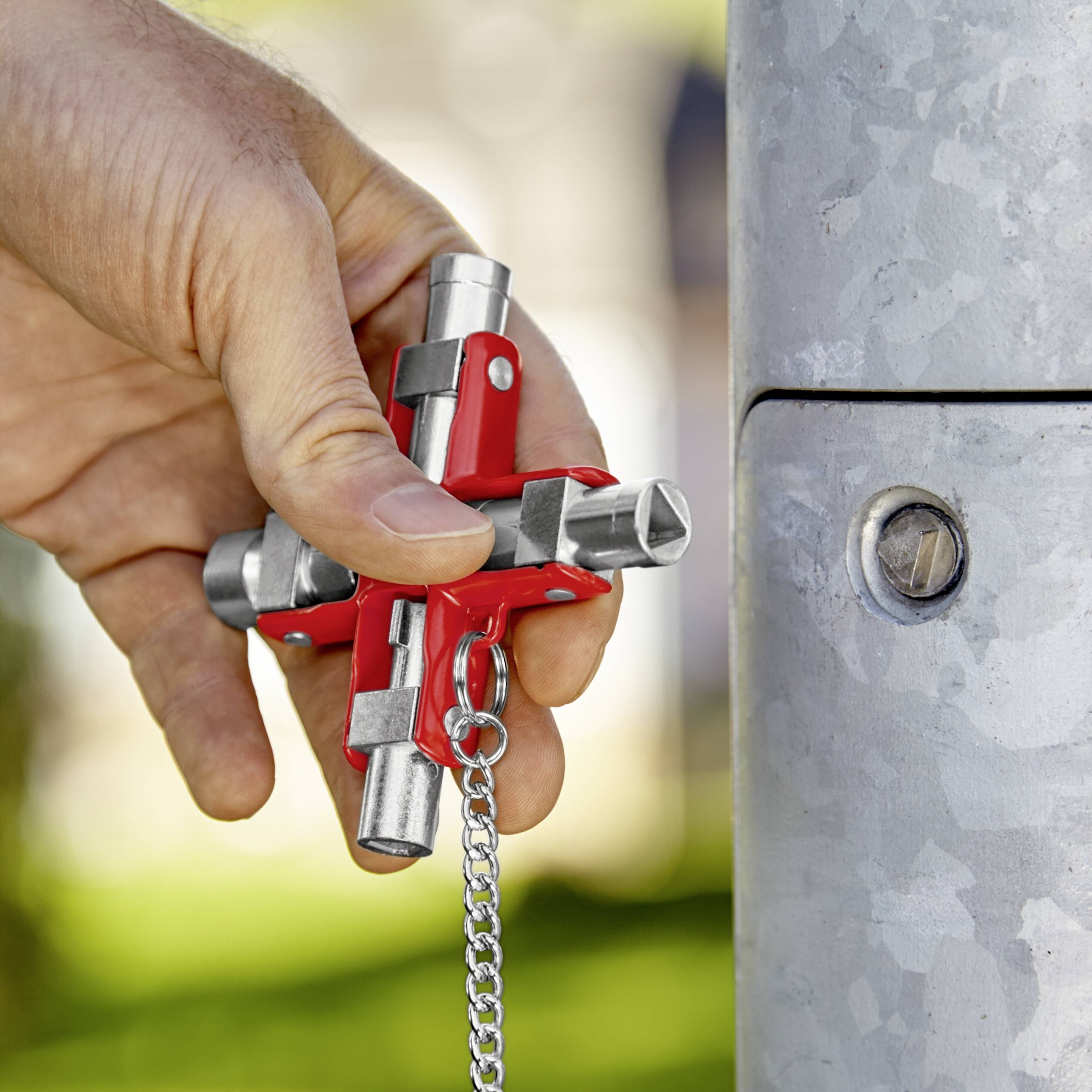 Eine Hand hält einen Vierkantschlüssel, der für den Zugang zu einem Schaltkasten an einem Stangenpfosten verwendet wird.