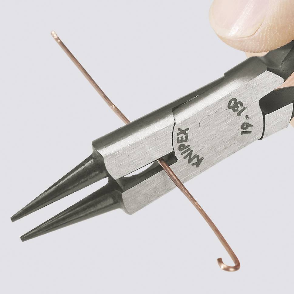 Eine Hand hält eine Zange, greift einen dünnen, gebogenen Kupferdraht. Die Zange ist schwarz mit silbernem Metallaufdruck.
