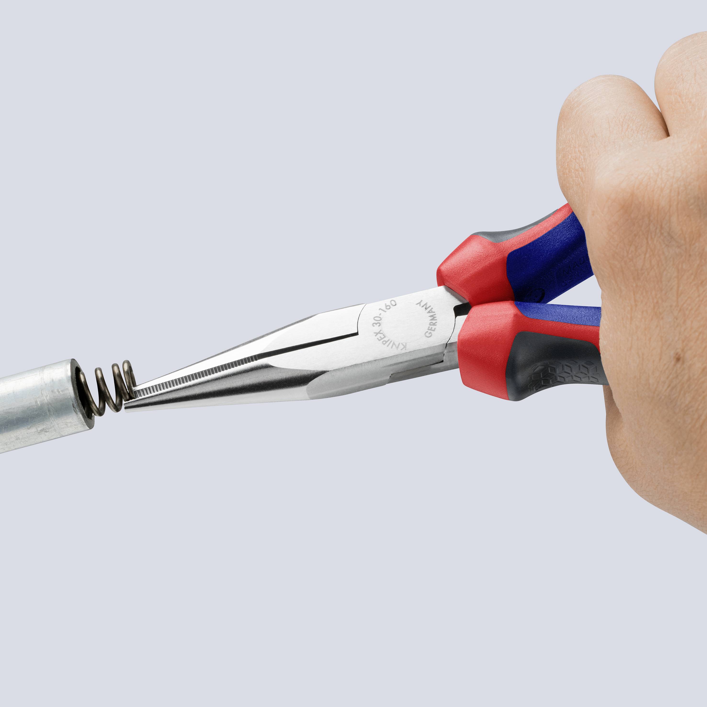 Eine Hand benutzt eine Zange, um eine Metallfeder zu halten. Sie ist dabei, die Feder in ein Rohr einzusetzen.