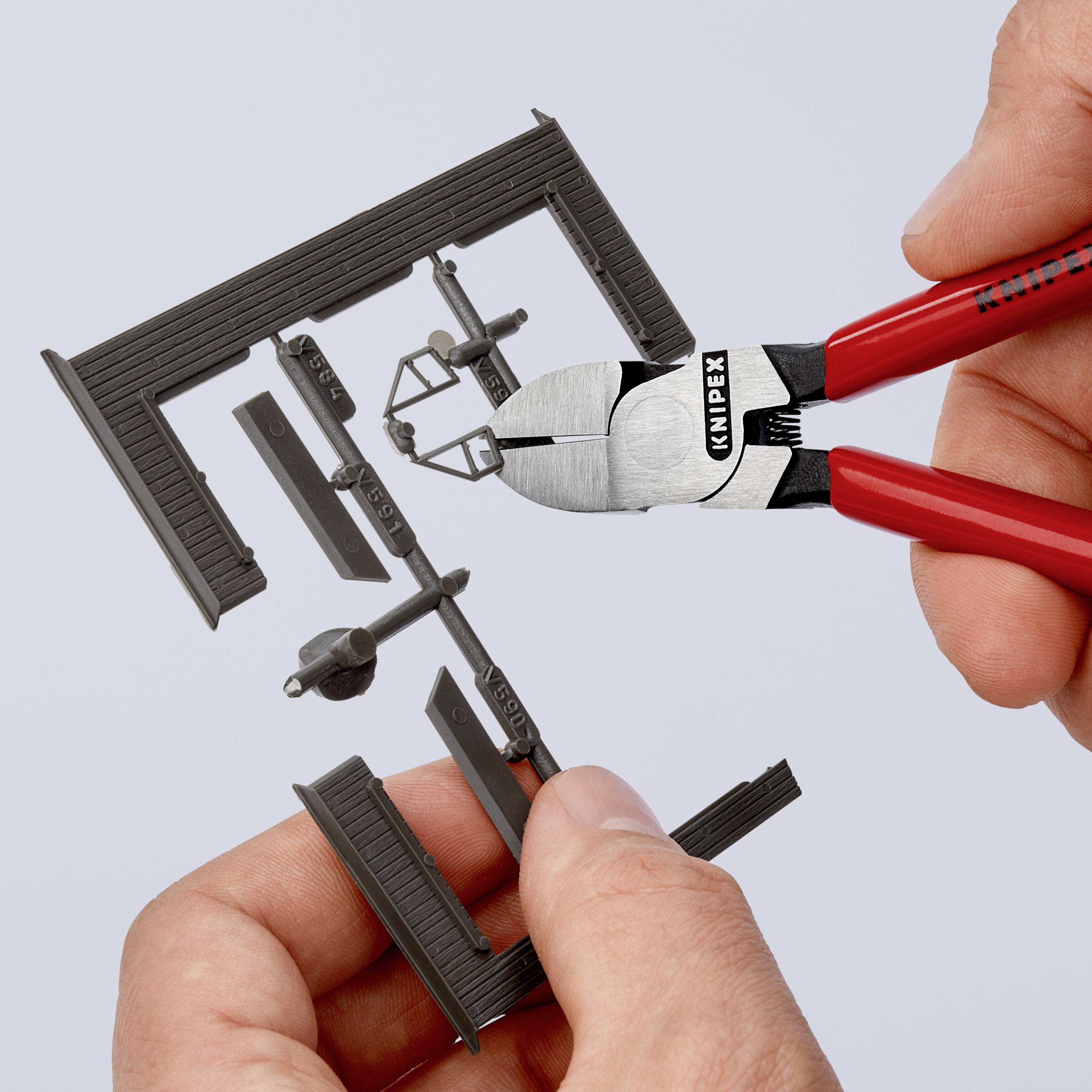 Zwei Hände halten eine Knipex-Zange, die einen schwarzen Modellbaurahmen schneidet.