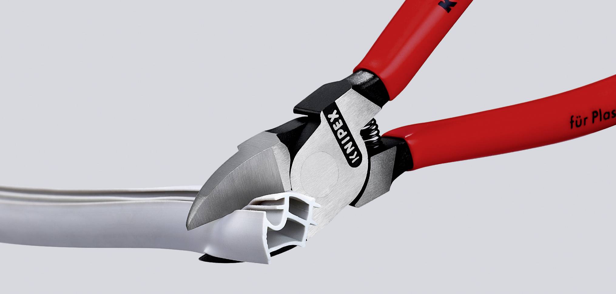Eine rote Zange schneidet einen weißen Kabelkanal. Der Schriftzug 'KNIPEX' ist auf der Zangenseite sichtbar.