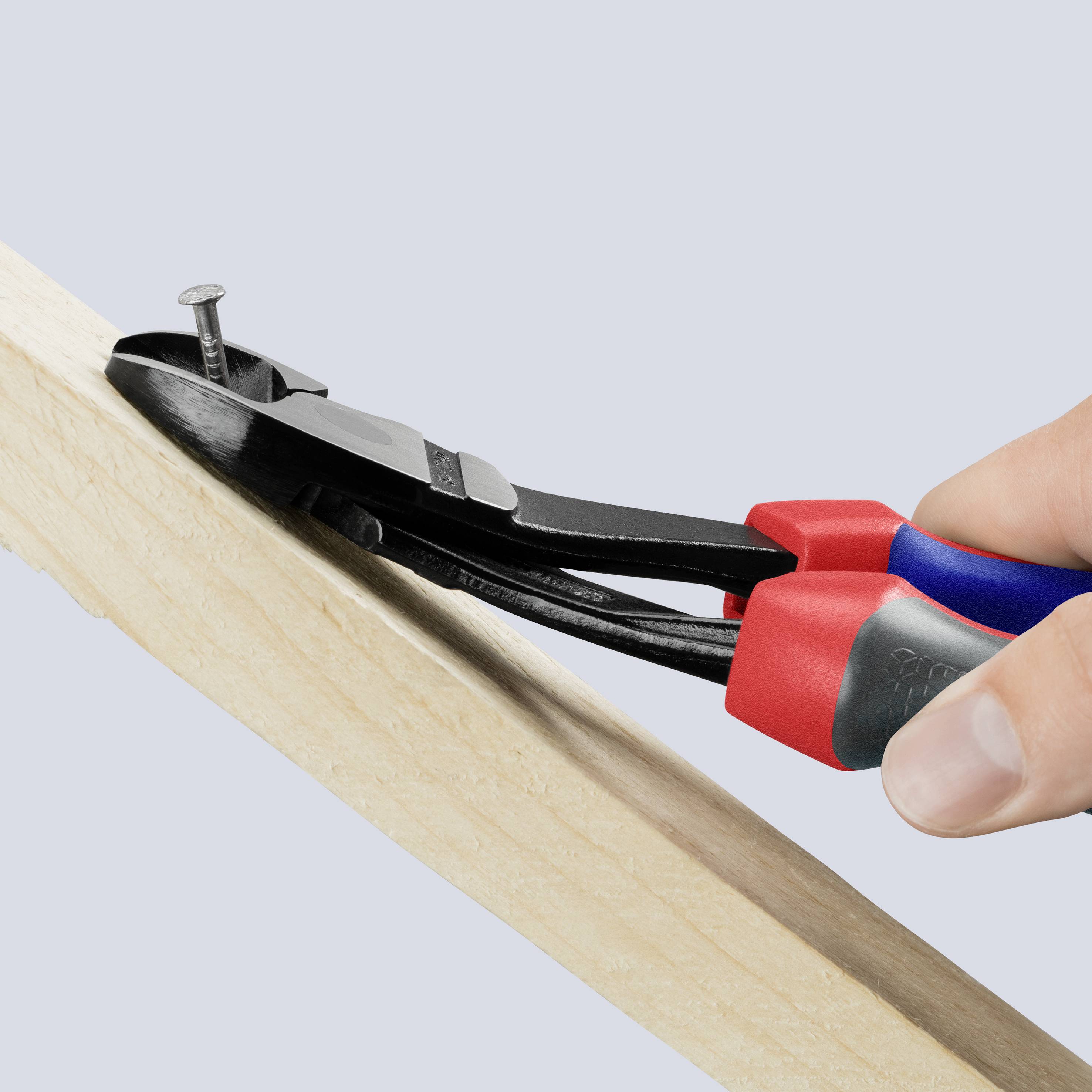 Hand, die mit einer Zange einen Nagel aus einem Holzbrett zieht.