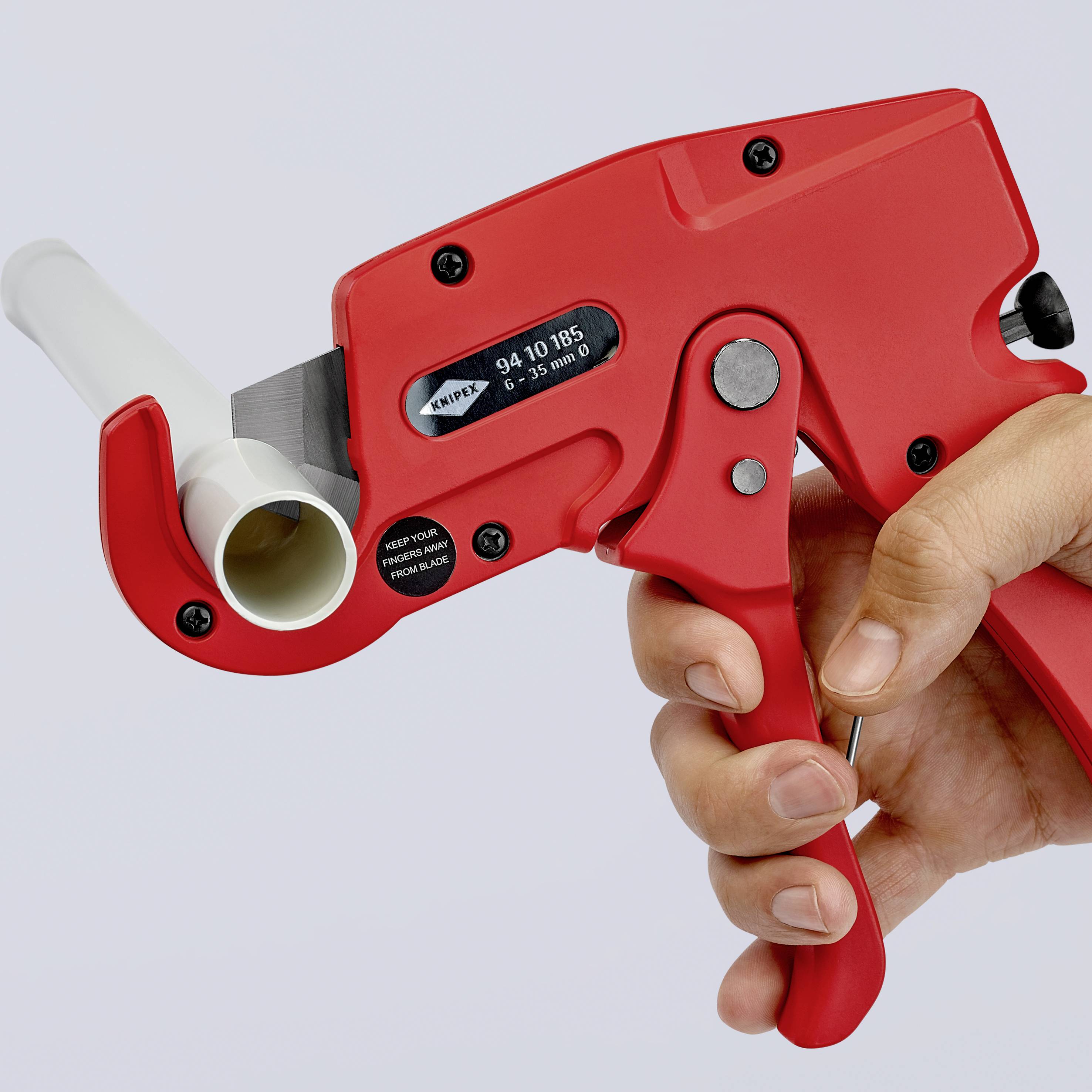 Eine Hand hält einen roten Paketbandabroller, bereit zum Gebrauch, mit einem weißen Klebeband auf der Rolle.
